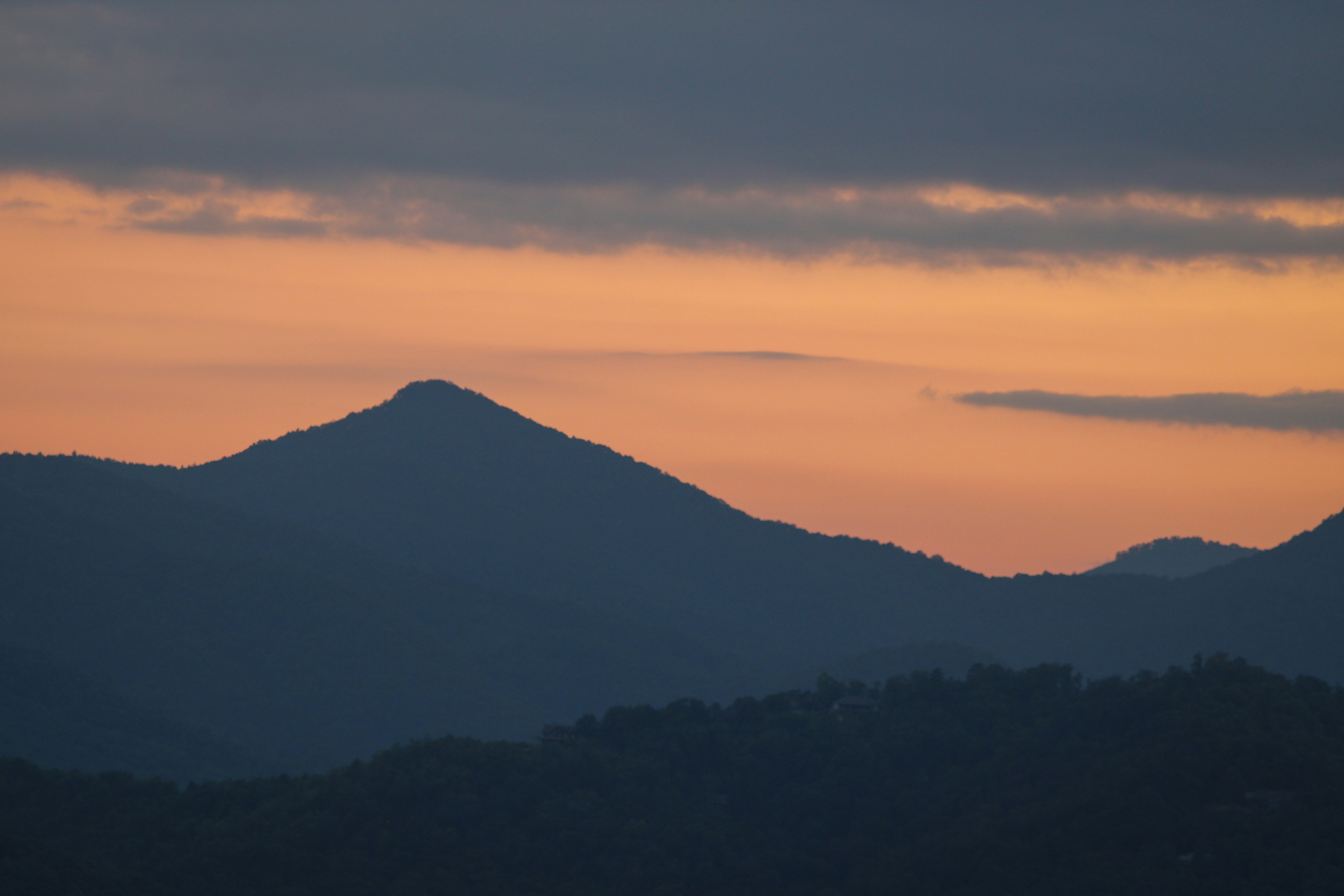 Mountains silhouetted against an orange sunset.