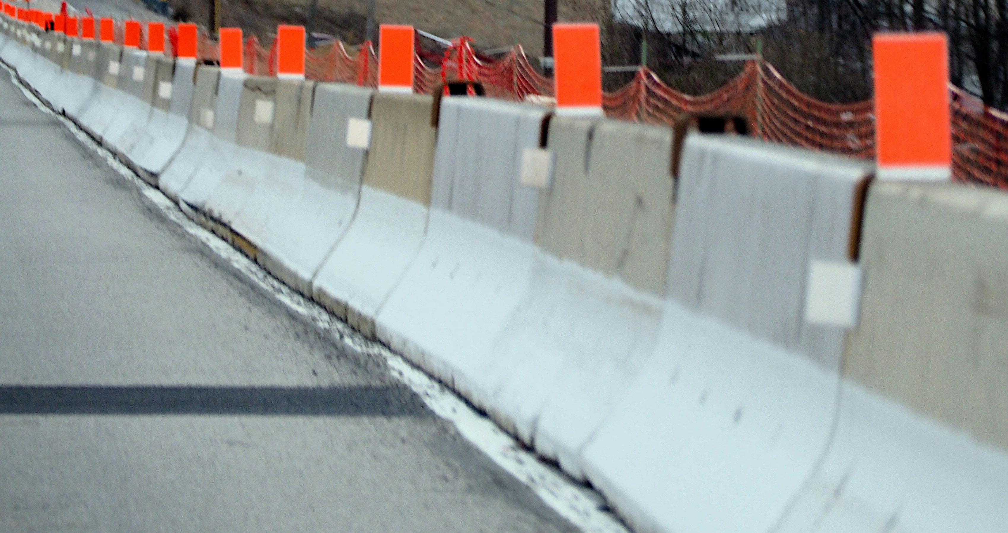 Road with concrete barriers and orange markers.