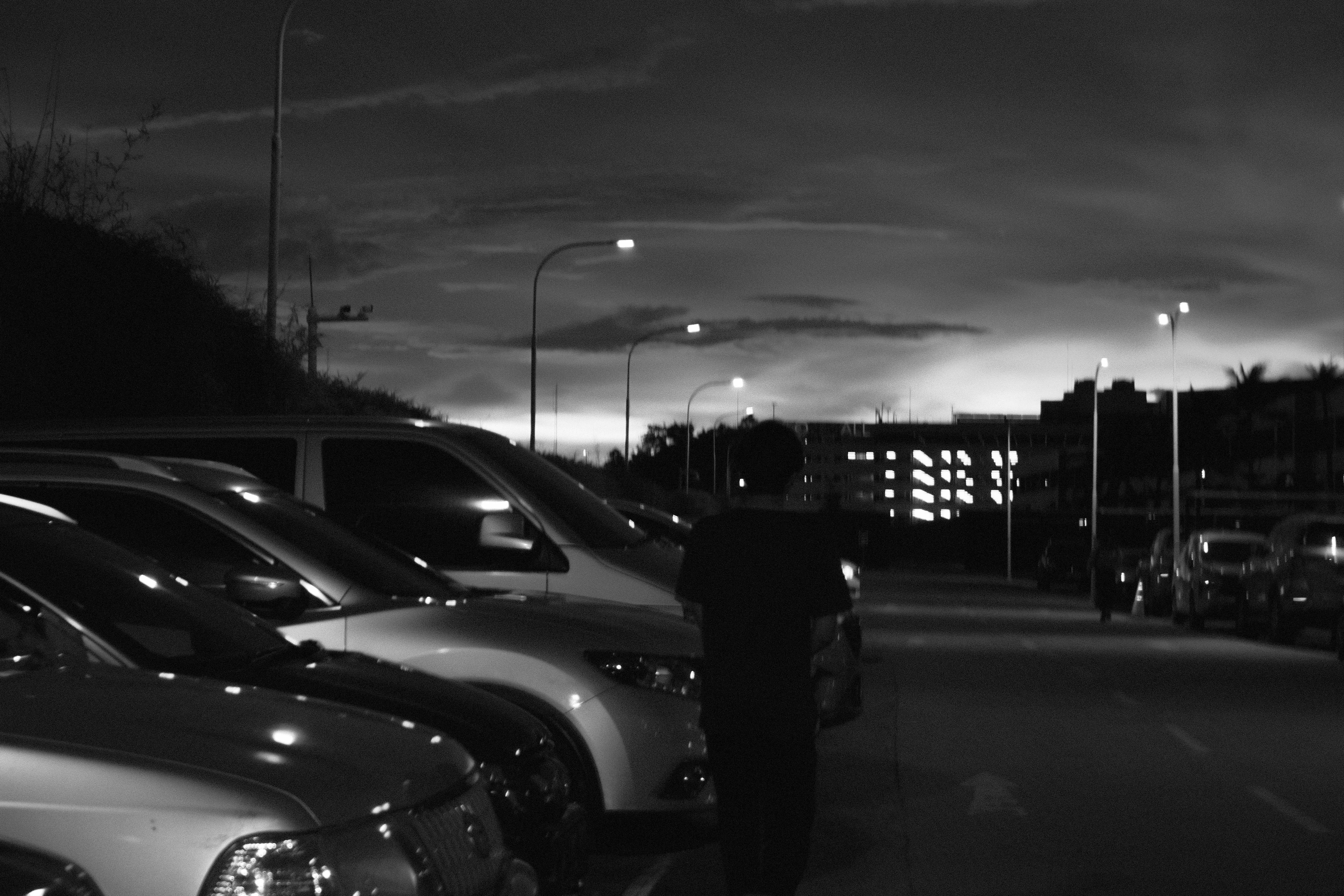 A person walks in a dark parking lot.