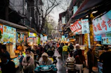 A bustling asian street market is filled with people