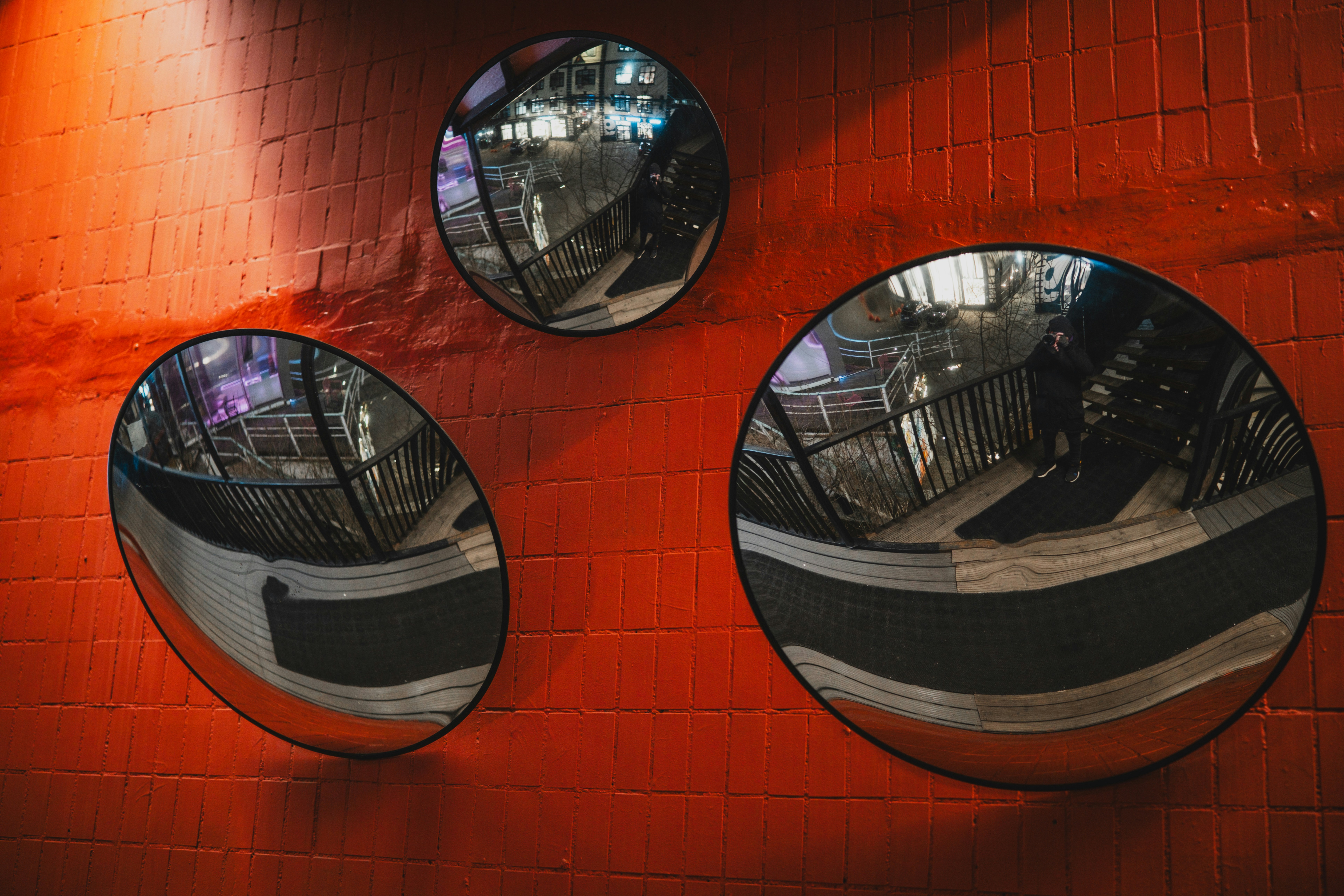 Three round mirrors are on a red brick wall.