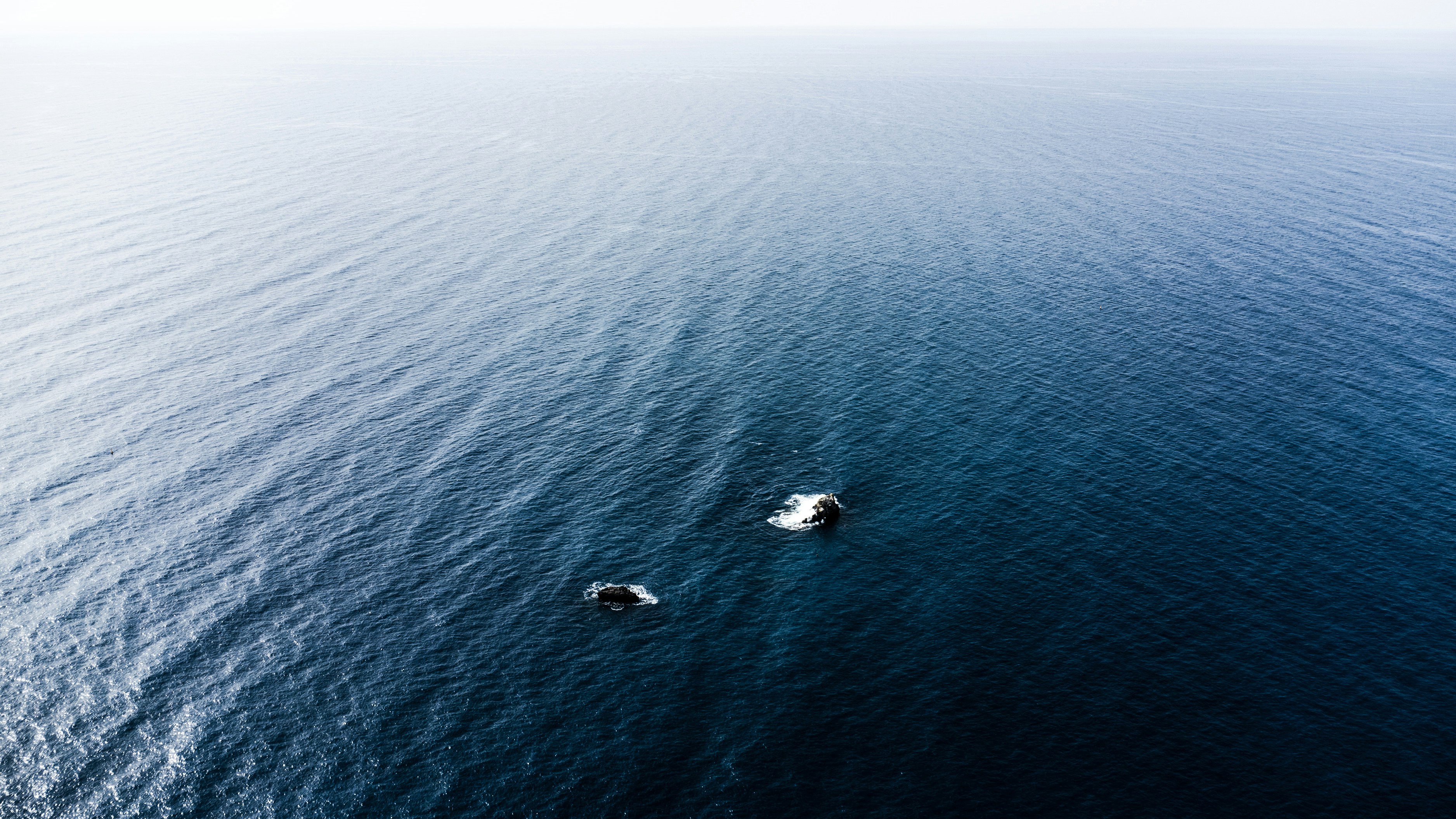 Two small boats float on vast ocean waters.
