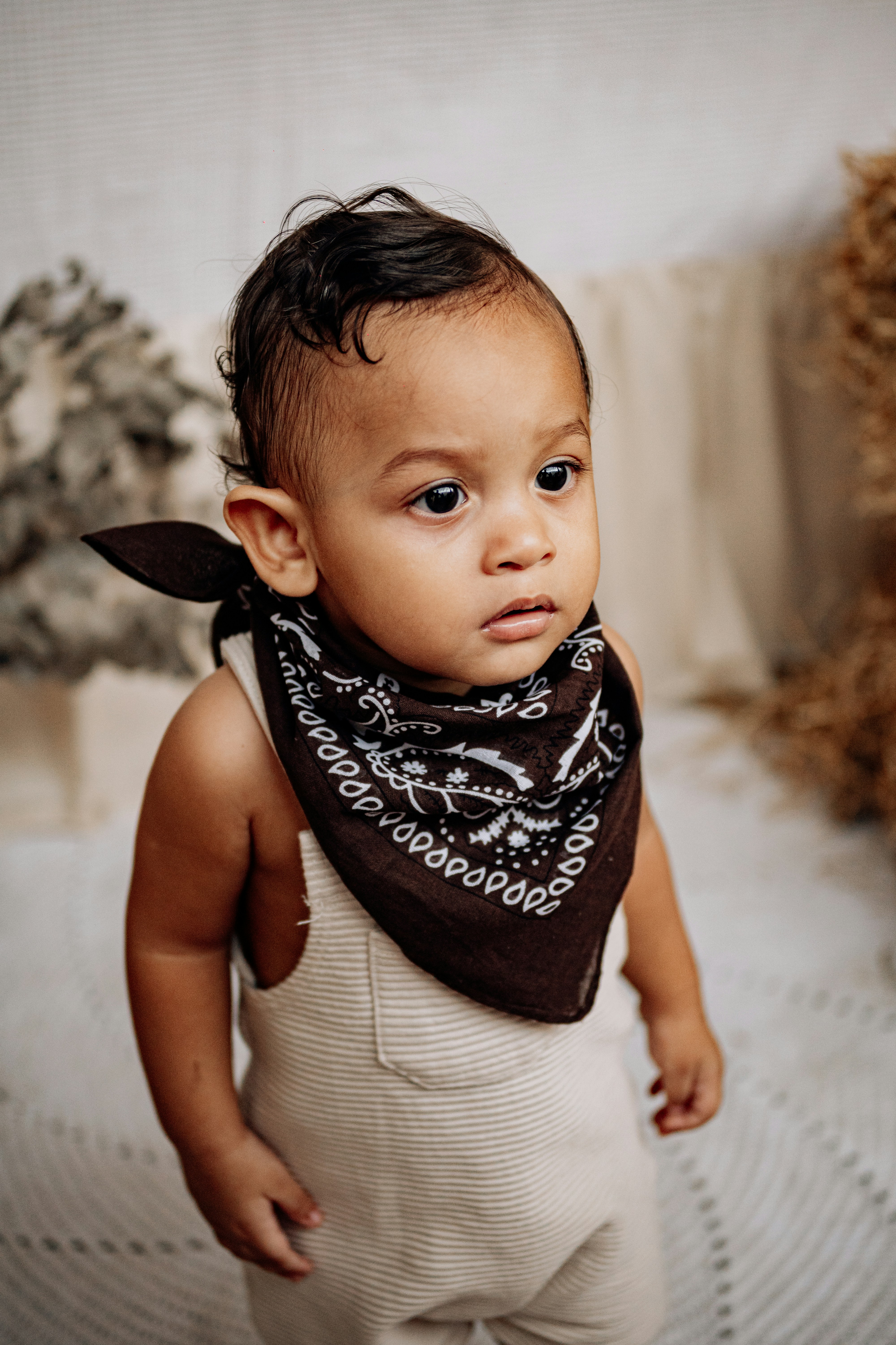 Adorable bebé con un pañuelo mira hacia otro lado.