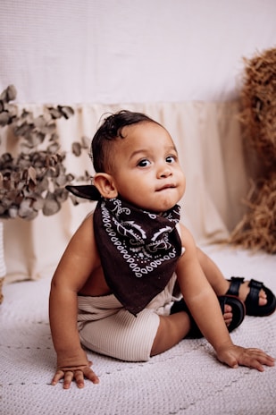 A cute baby with a bandana looks at the camera.