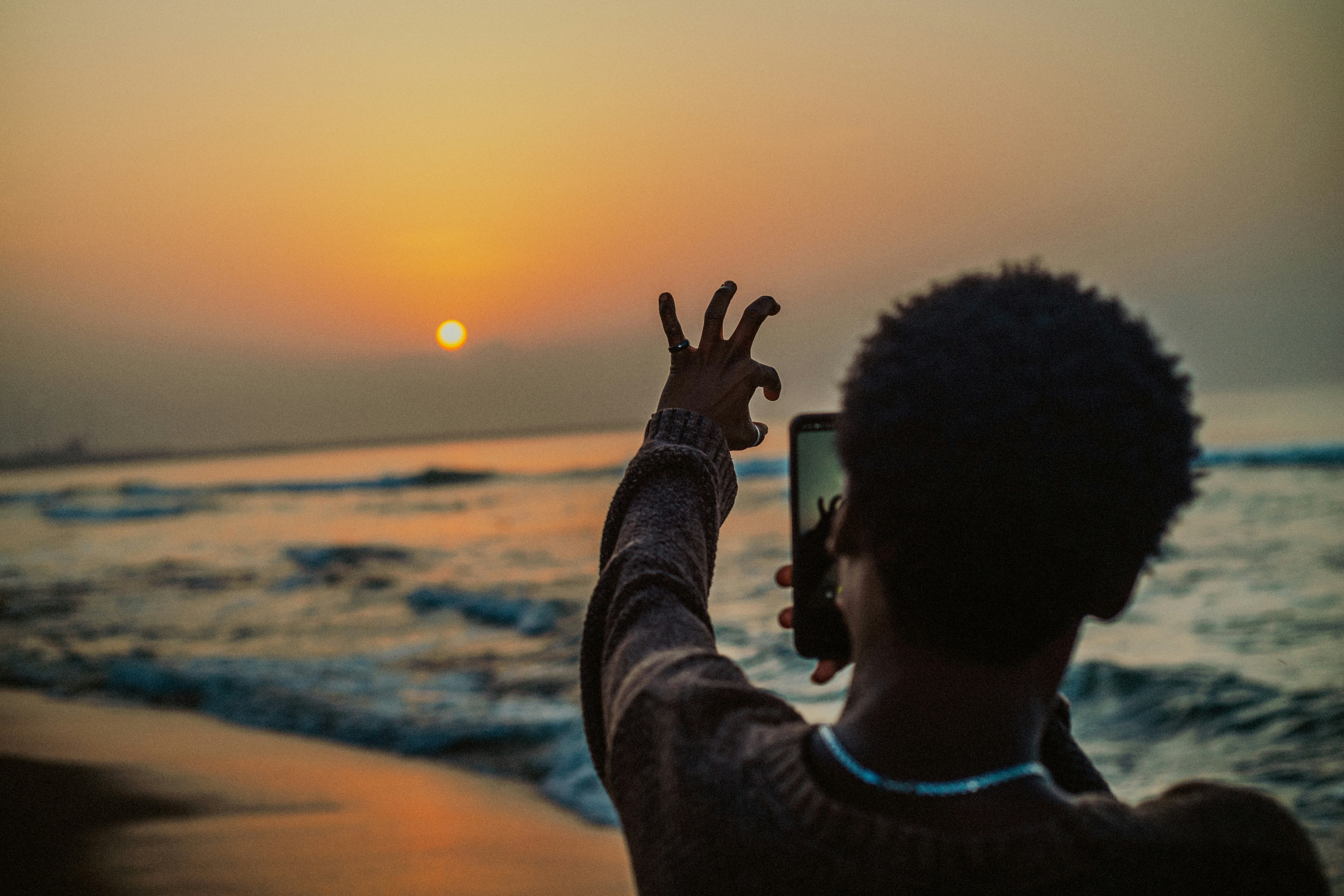 Person taking a photo of the sunset at the beach