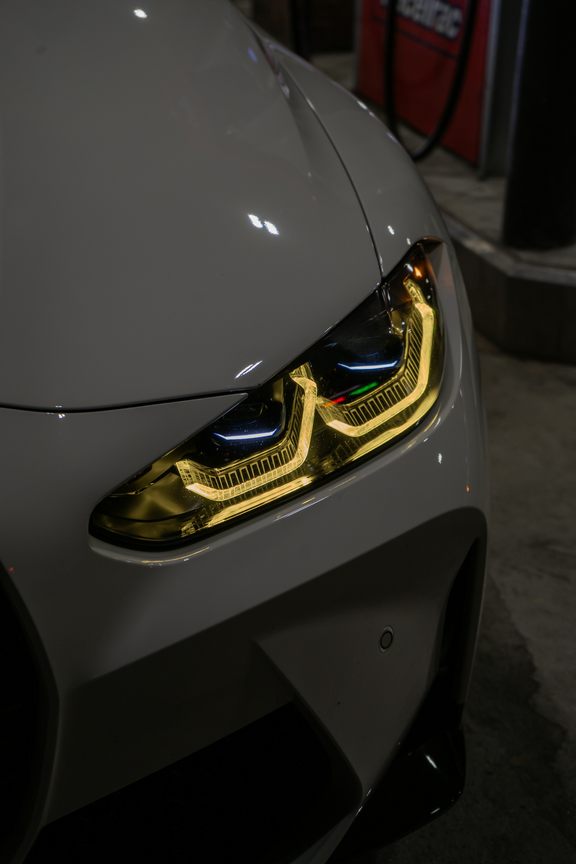 A sleek car headlight illuminated at night.