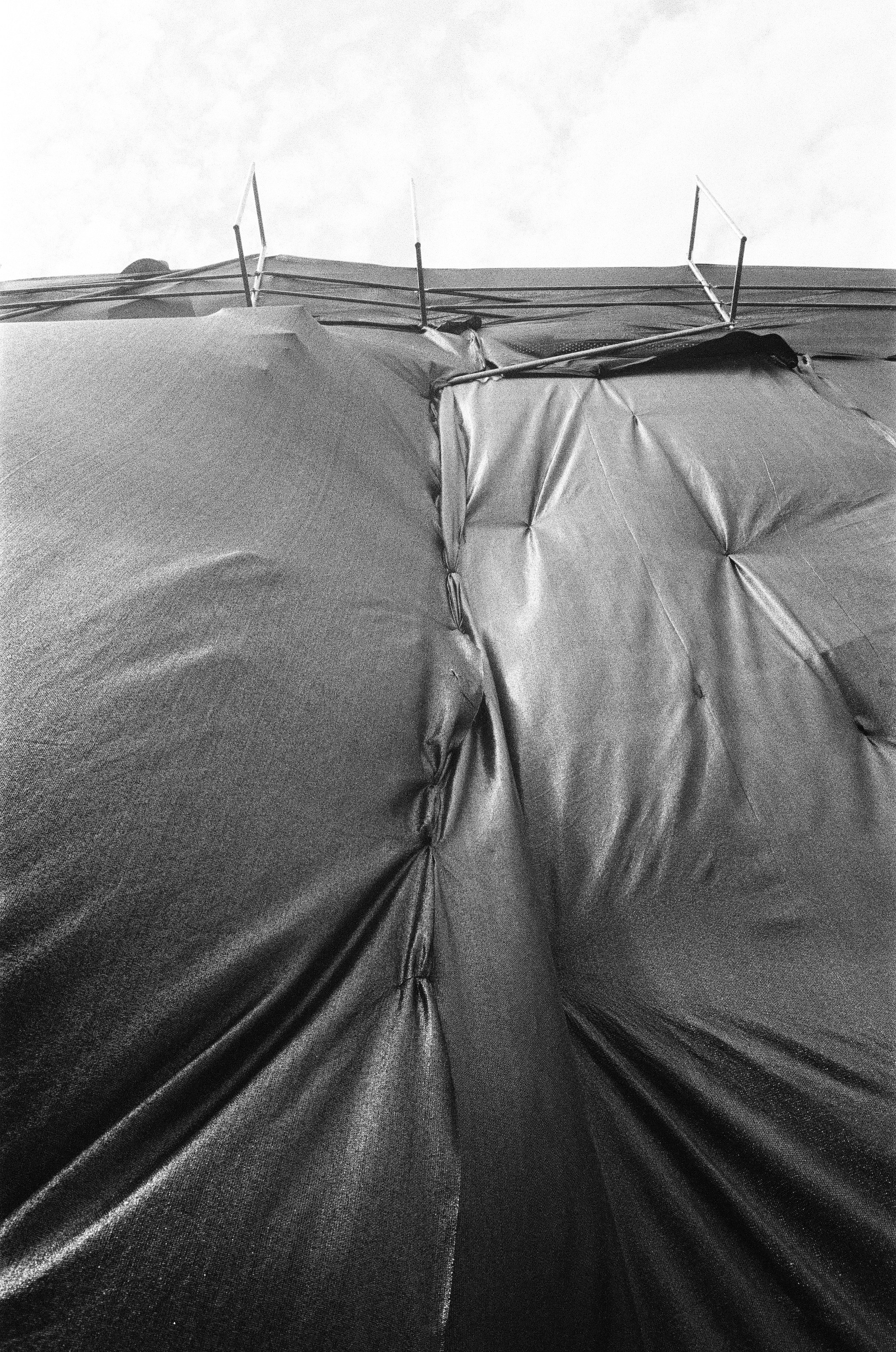 Black tarp covers something in front of a sky