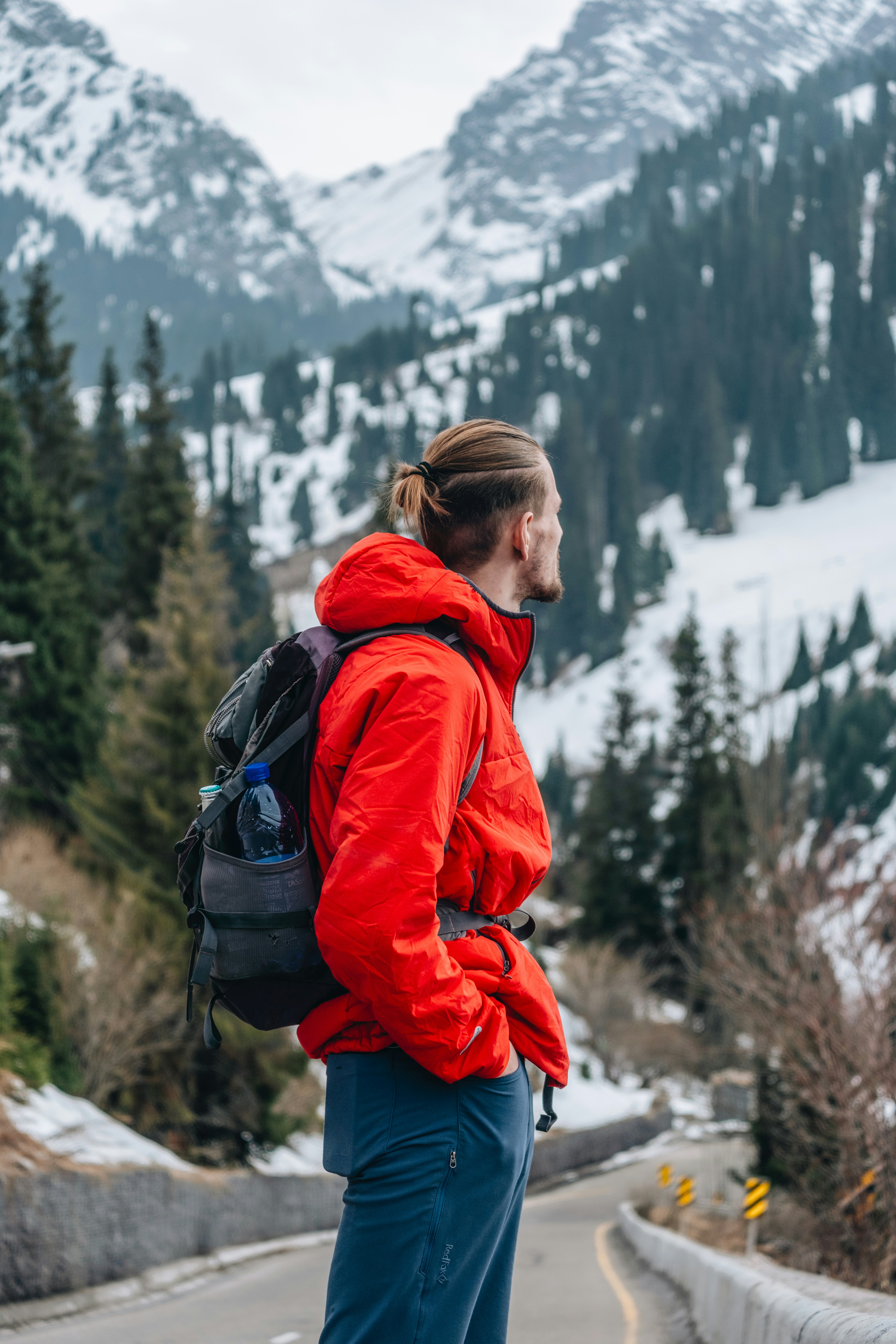 Man in red jacket looks at snowy mountain vista.