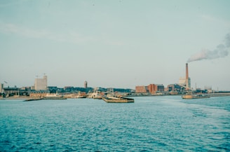 Harbor view with buildings and smoke stacks.
