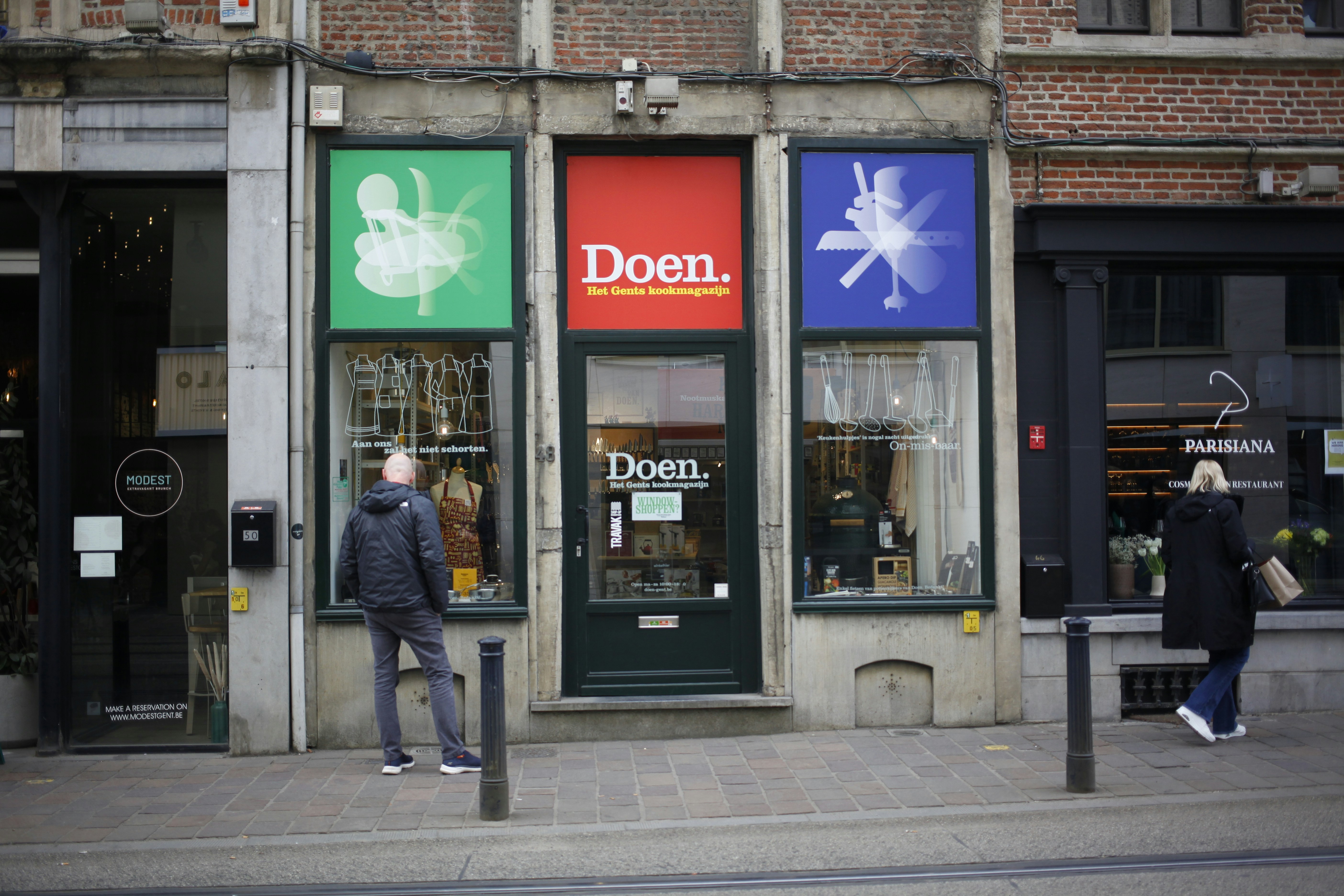 A shopfront with colorful signage and people.