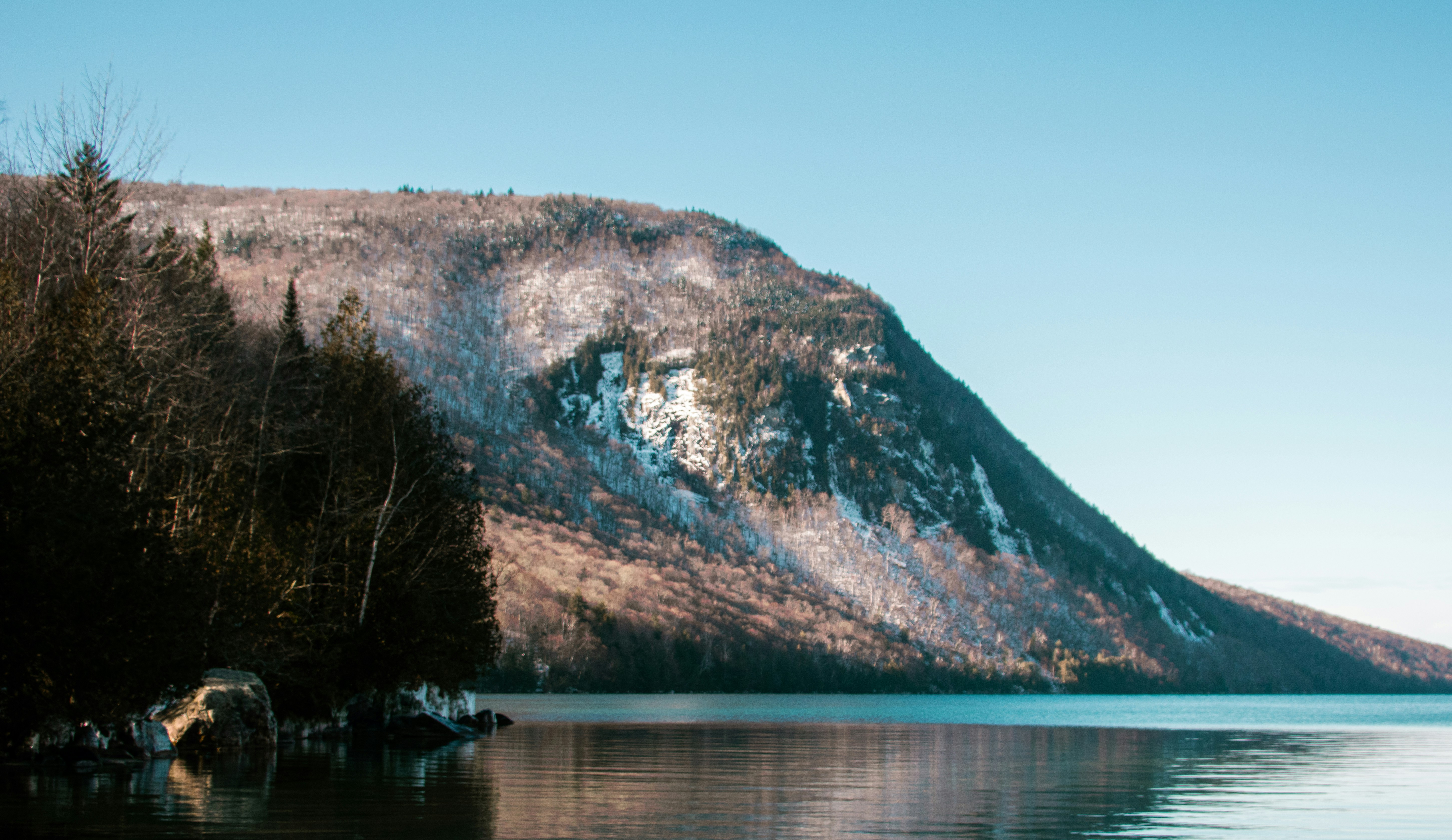 A mountain rises beside tranquil waters.