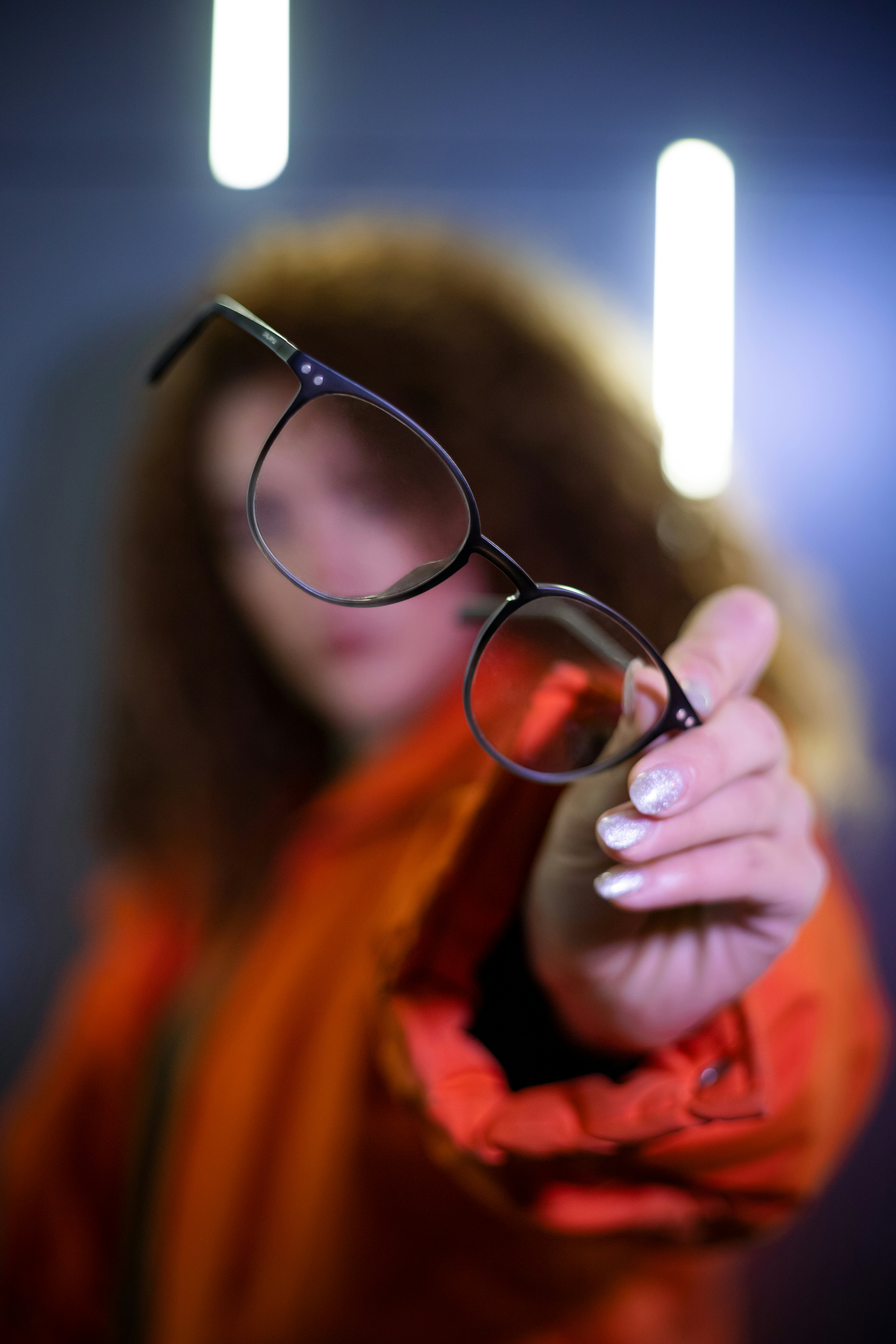 Woman holds out glasses for the camera.