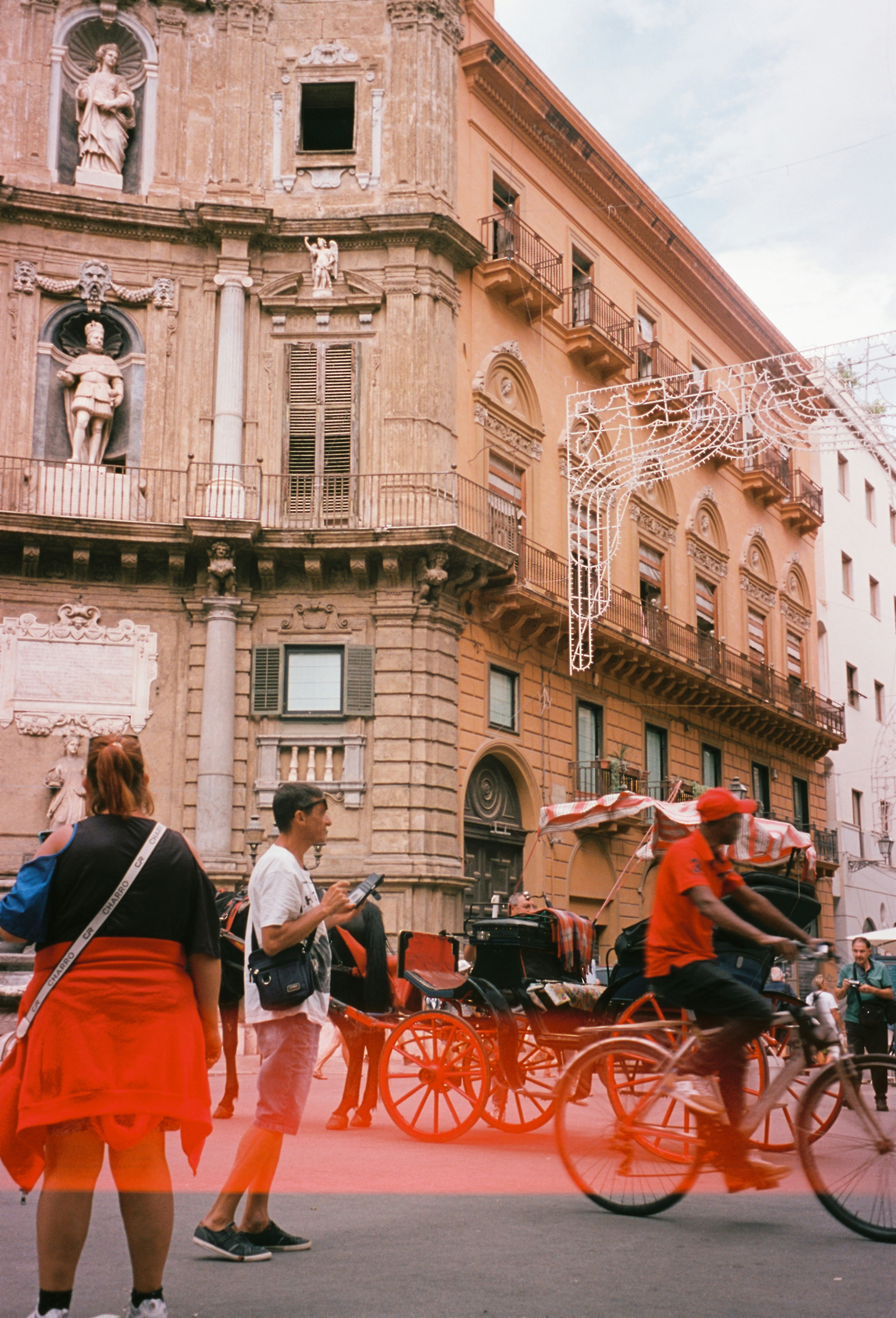 Personas y carruajes tirados por caballos en una plaza de la ciudad.