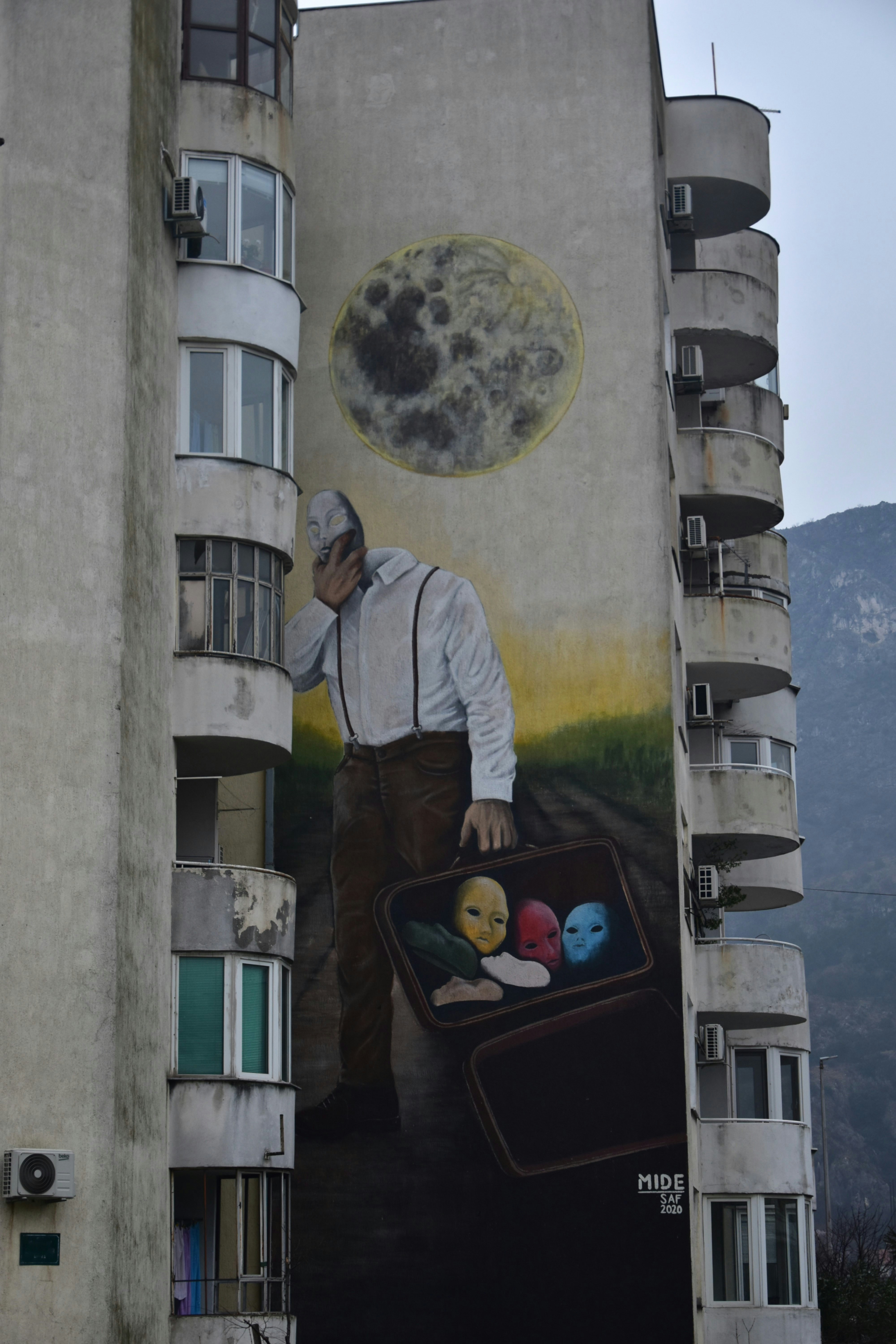 A mural of a man with suitcase and masks.