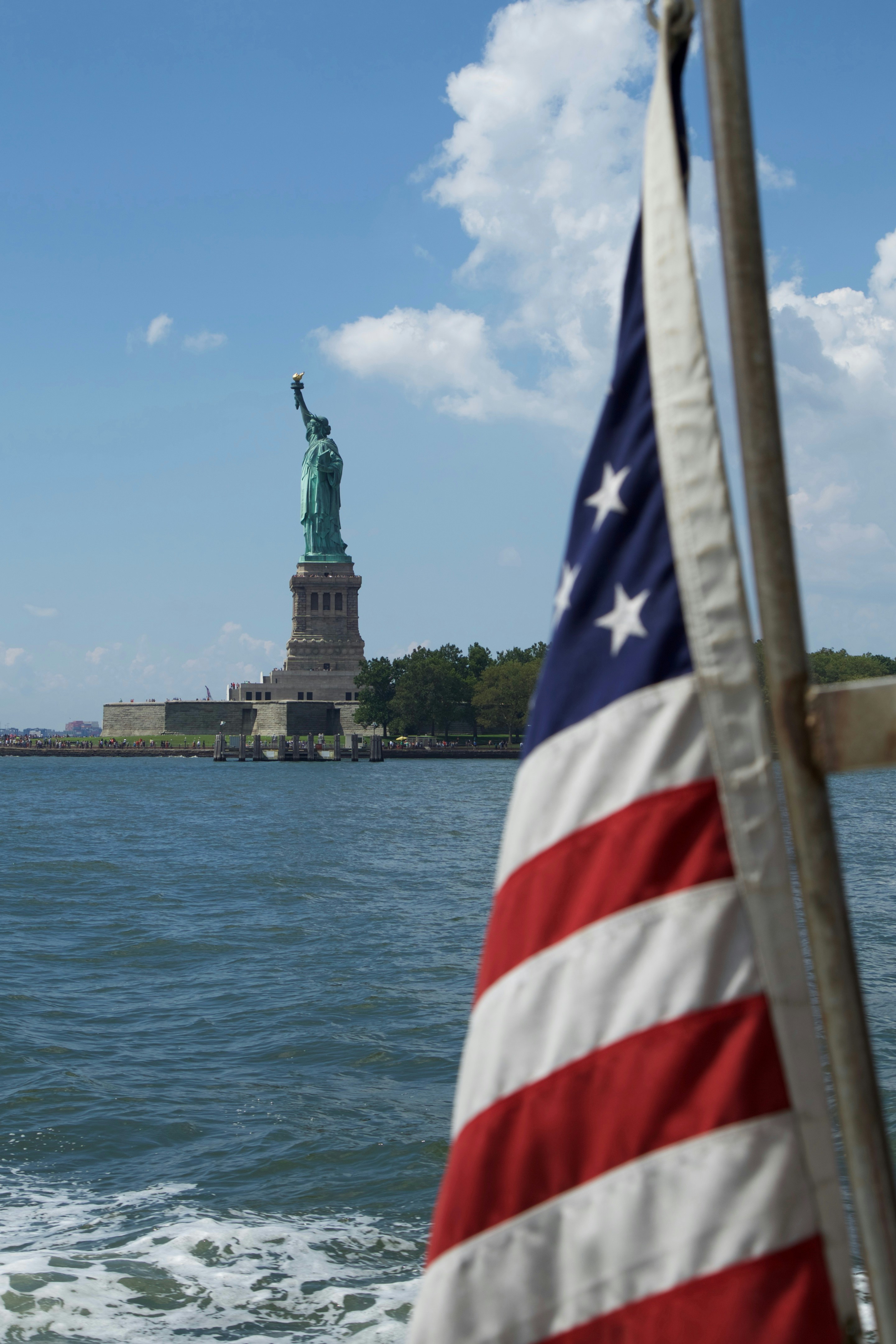 The statue of liberty stands tall behind the flag.