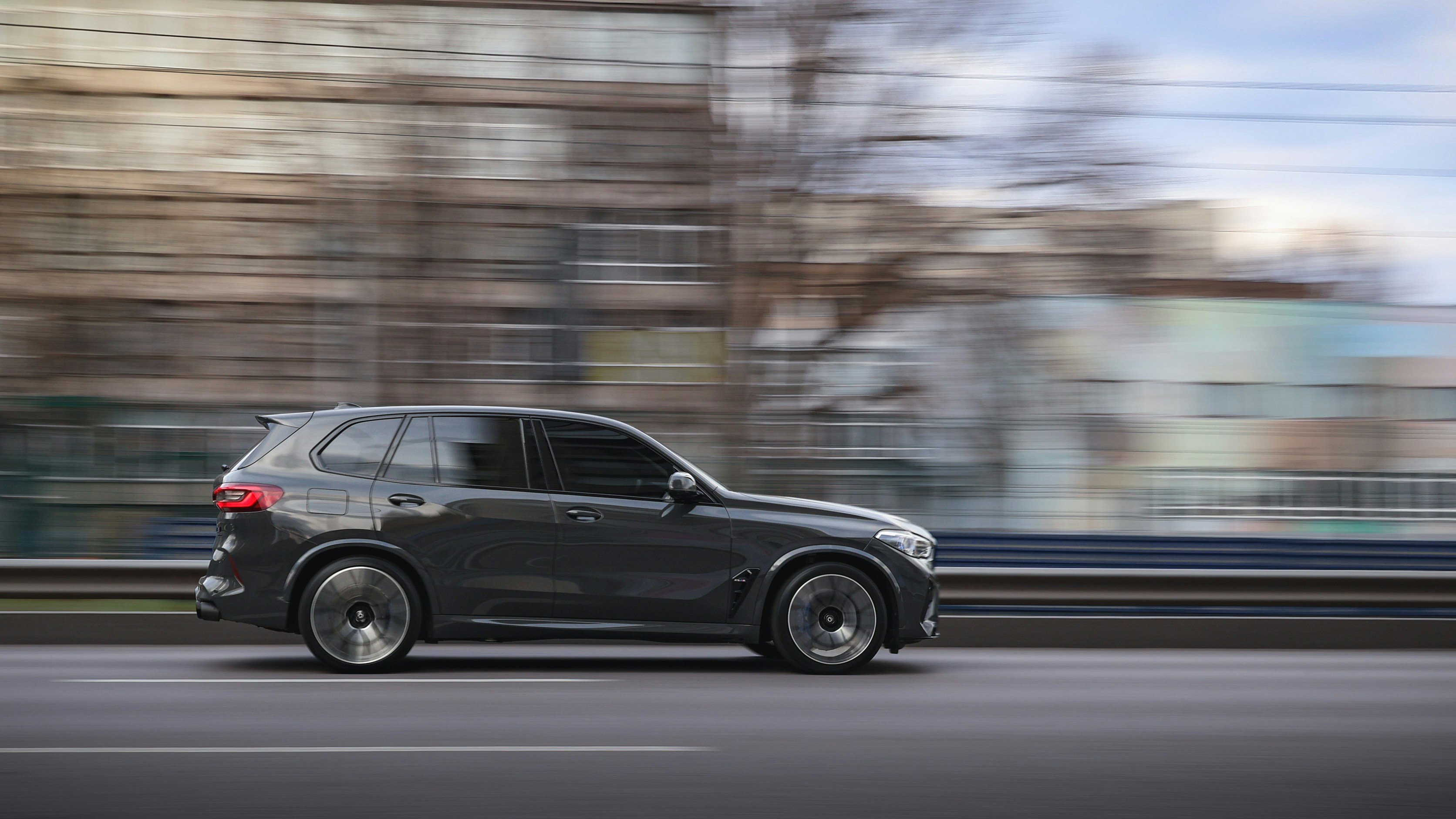 A black suv is speeding down a city street.