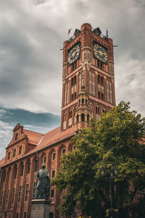 A brick tower with clocks and a cloudy sky.