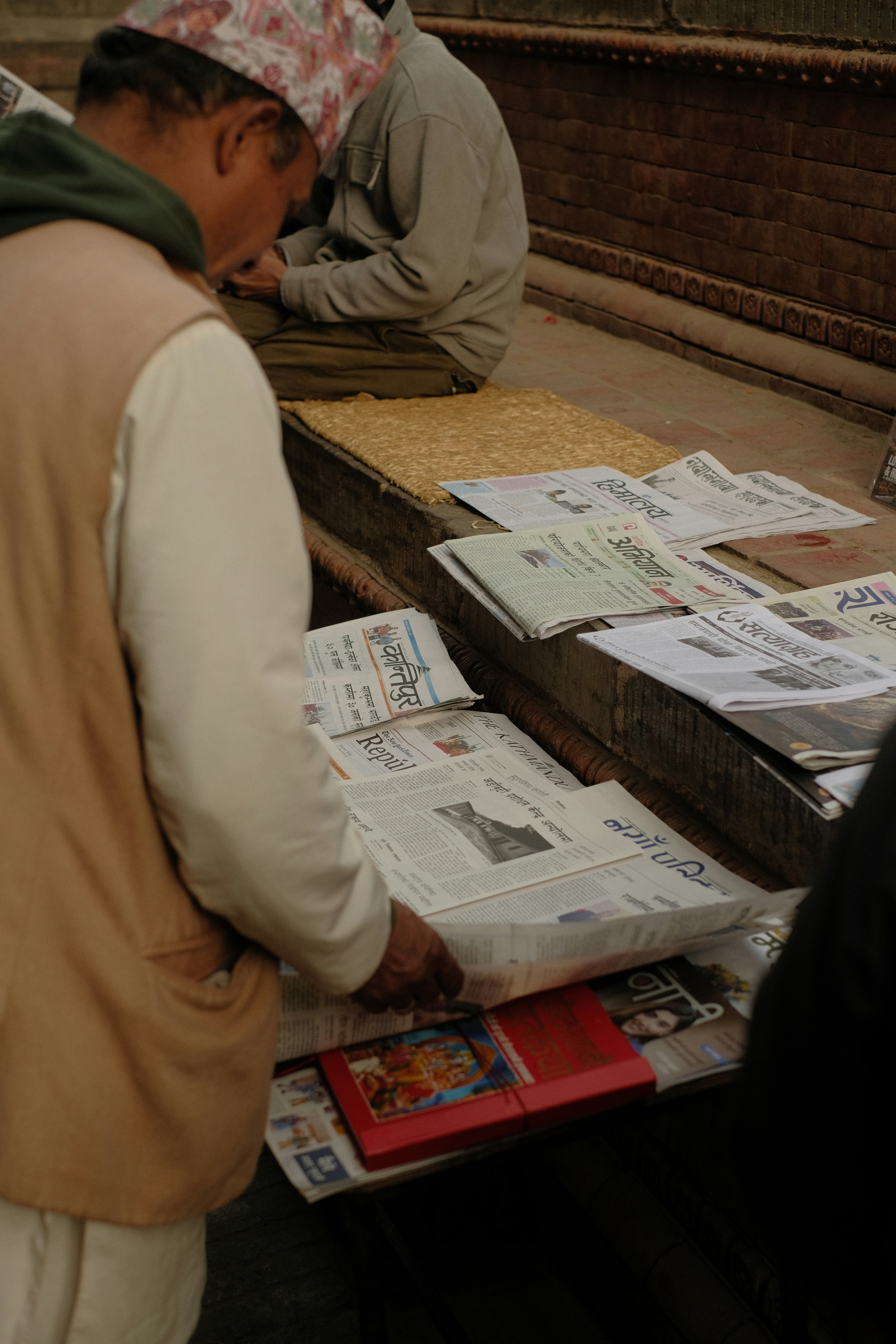 Man is reading newspapers in a local market.
