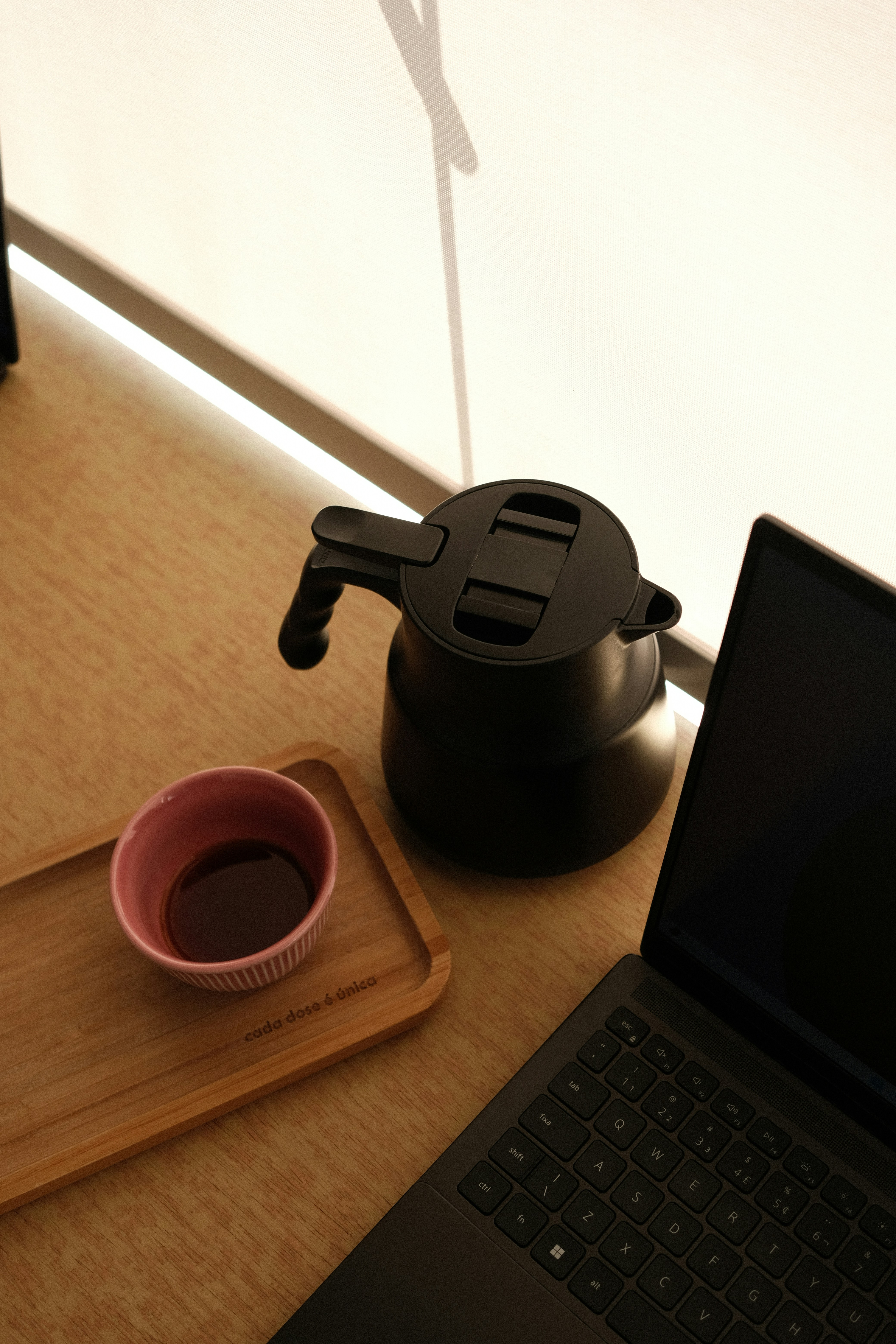 Laptop on a desk beside a coffee cup and a kettle, suggesting a focused work routine
