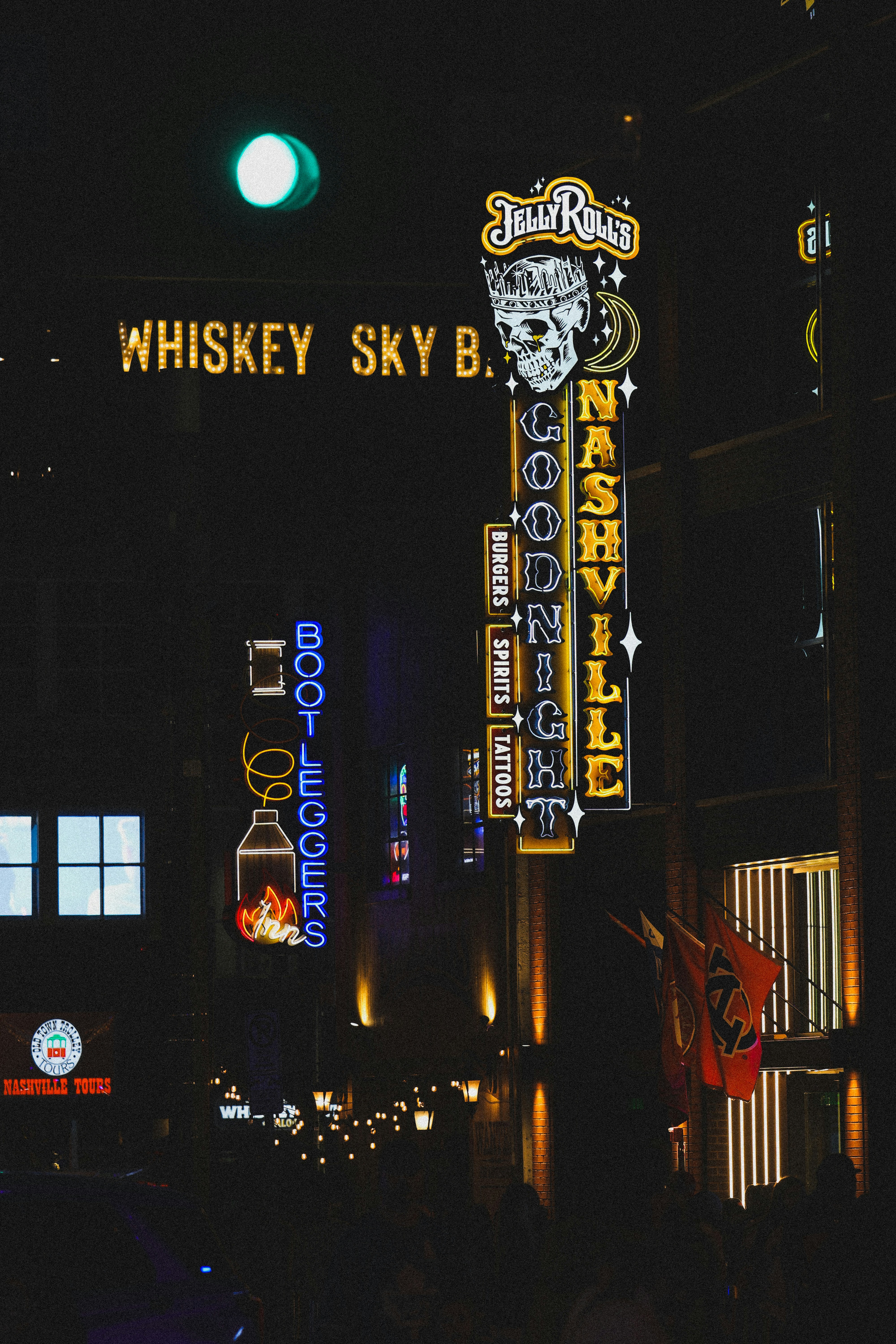 Neon signs illuminate a night scene in nashville.
