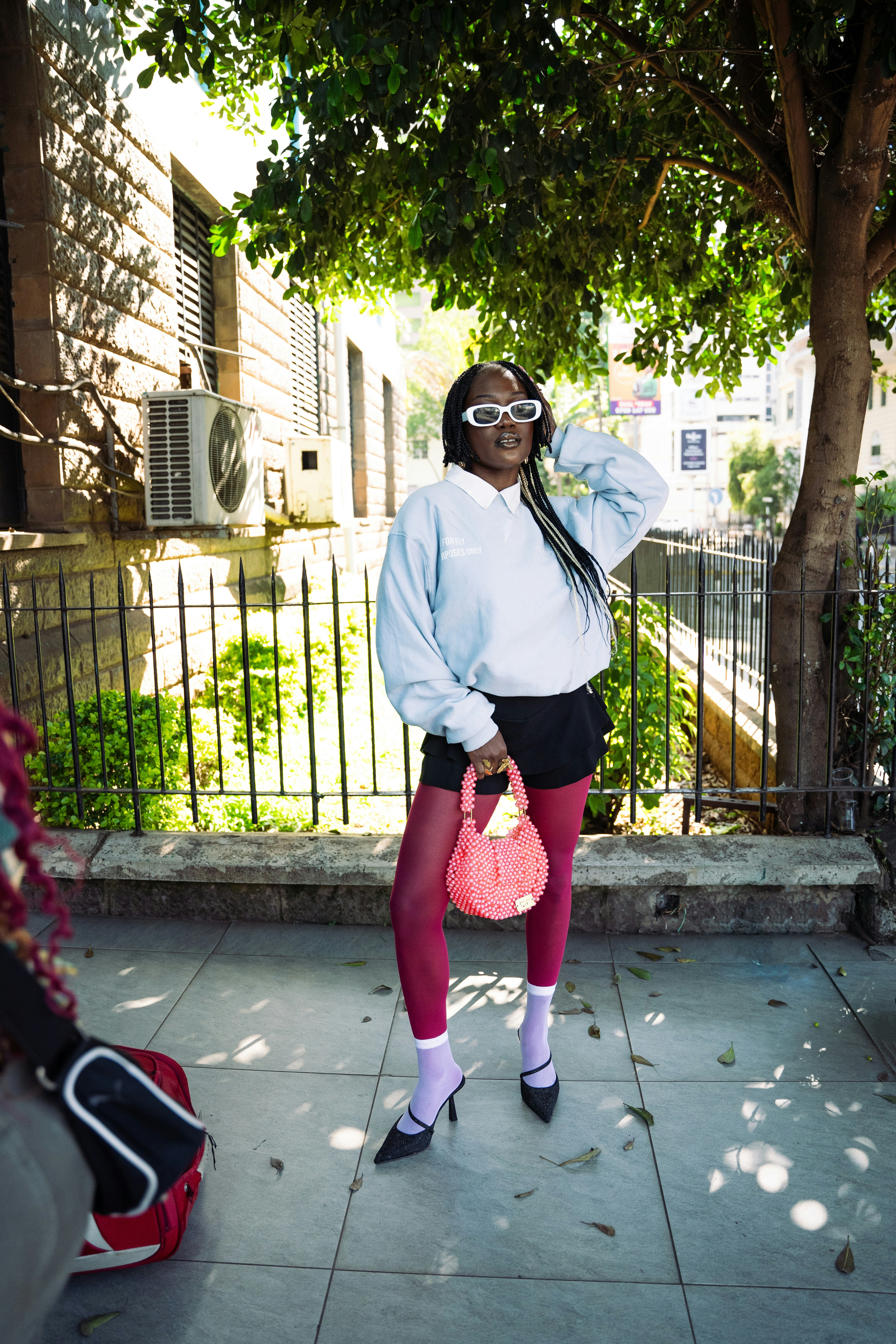 Woman in sunglasses and stylish outfit poses.