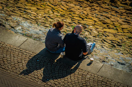 Two people sit enjoying the sunny cobblestone view