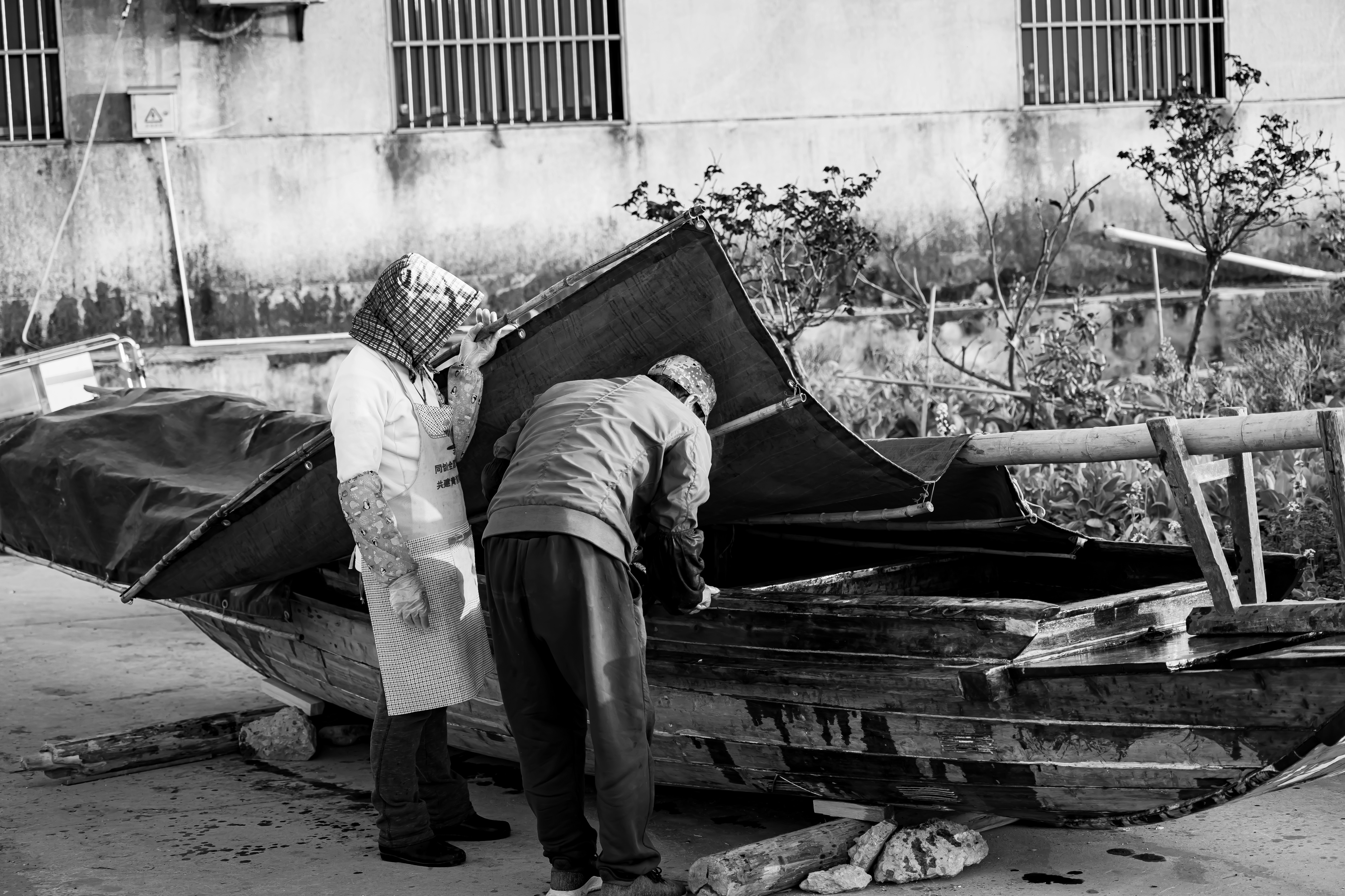 Two people inspect a damaged boat.