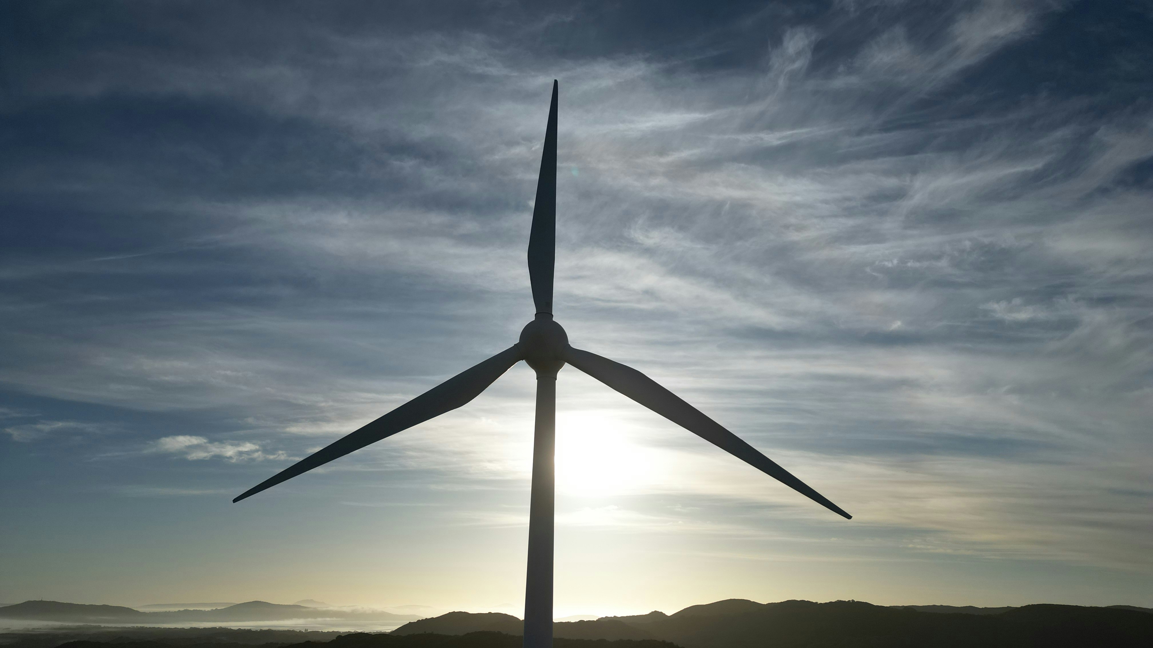 Wind turbine silhouetted against a cloudy sky.
