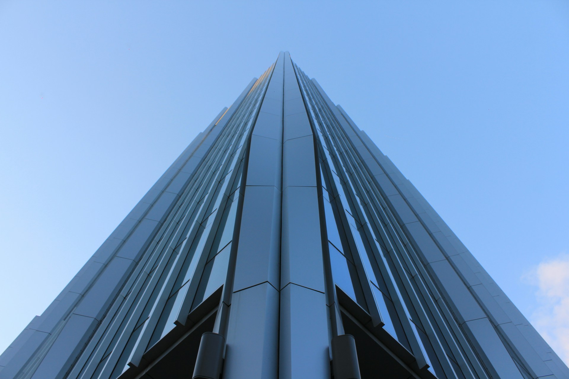 An angular skyscraper rises into the blue sky.