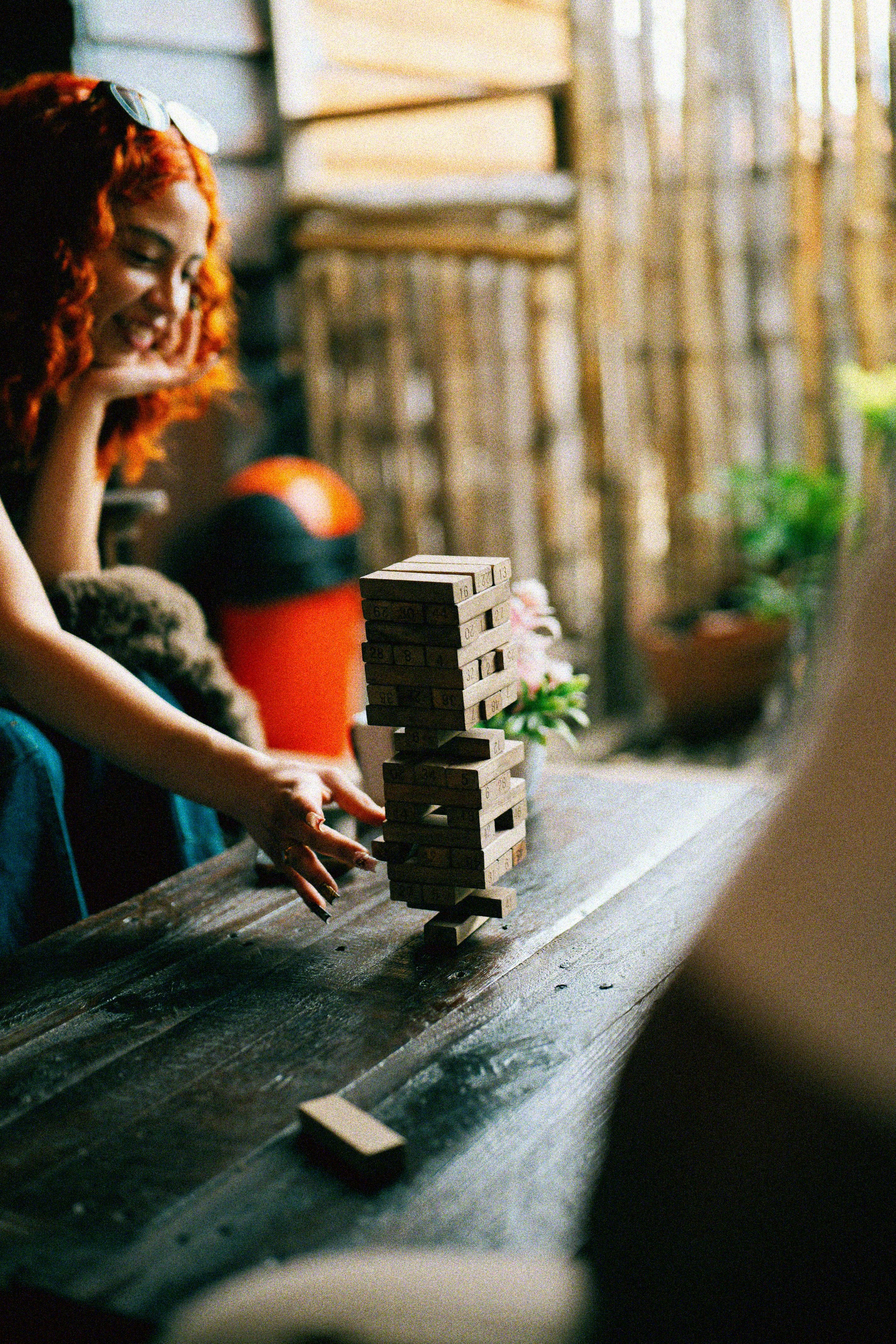 여자가 나무 테이블에서 젠가 게임을 하고 있다.