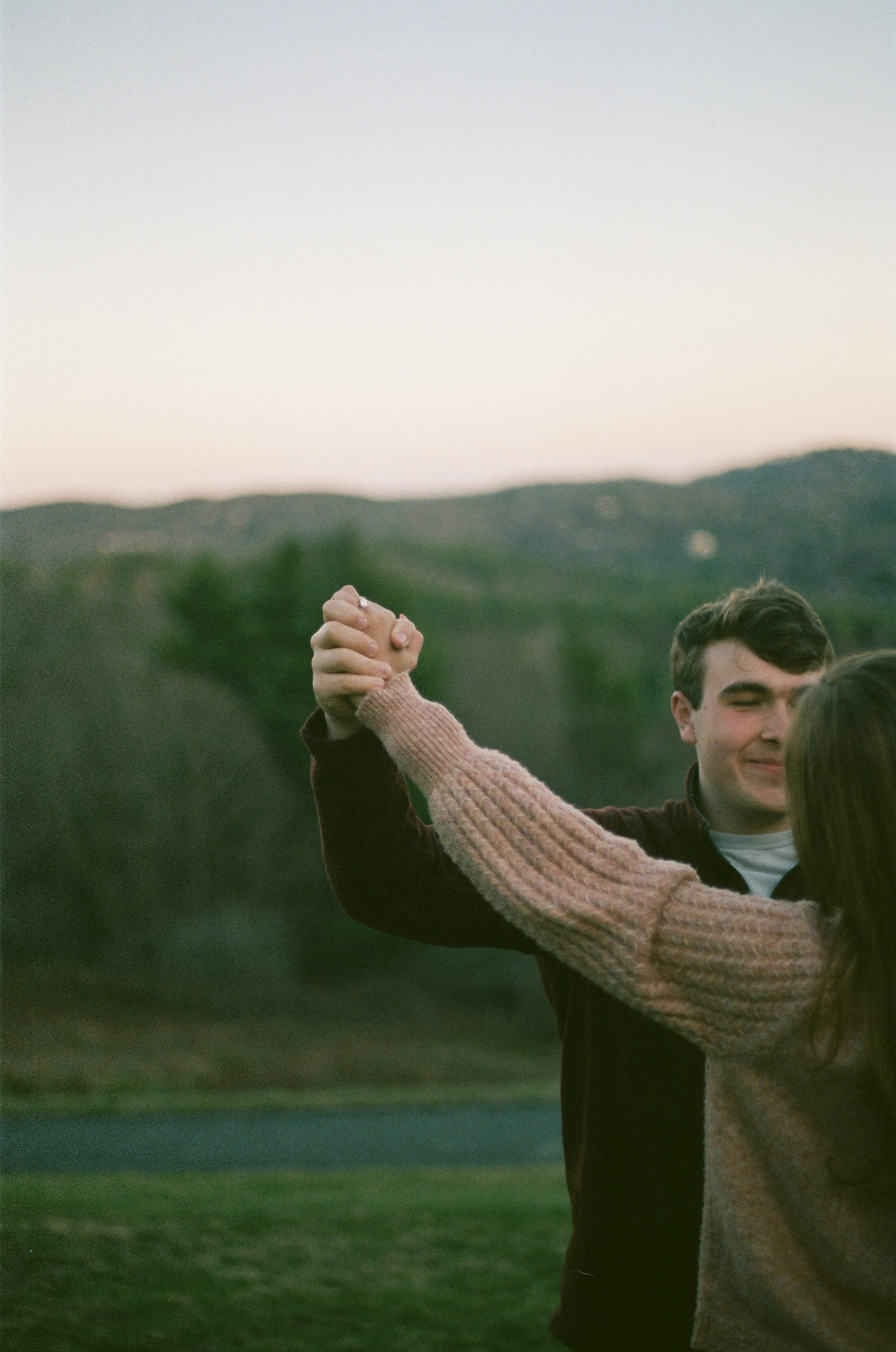 A couple dances outdoors, holding hands