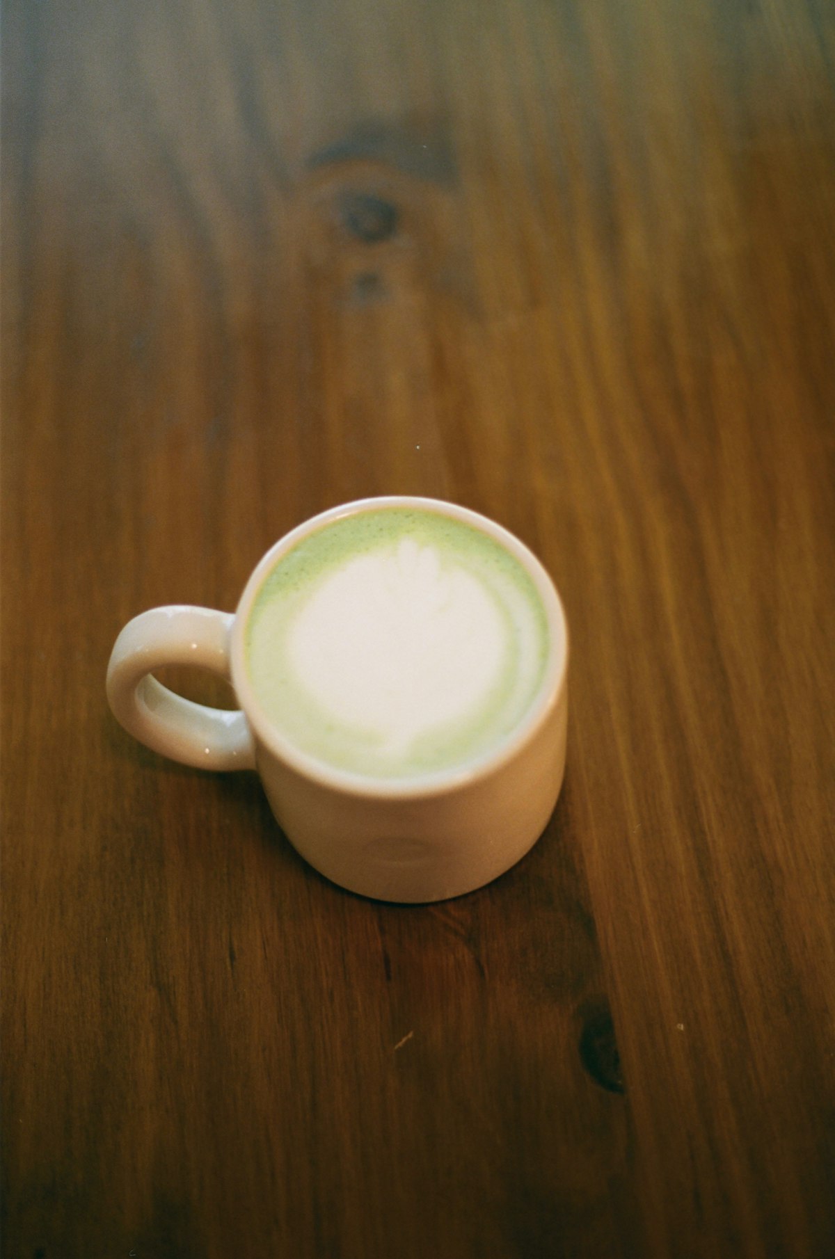 Matcha Latte in einer Keramiktasse auf einem Holztisch, serviert in einem Lausanner Specialty Café