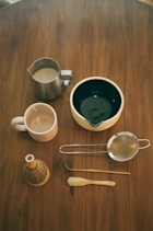 Tea making tools are arranged on a wooden table.
