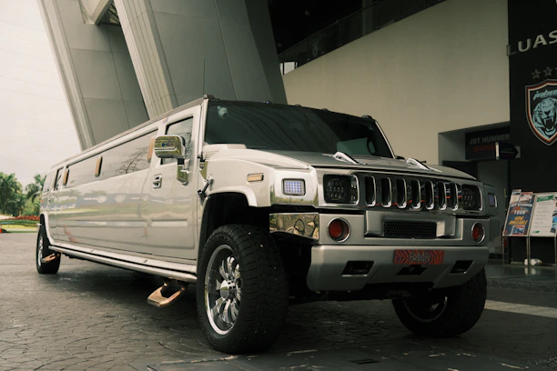 A silver hummer limousine is parked outside.