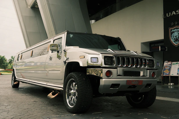 A silver hummer limousine is parked outside.