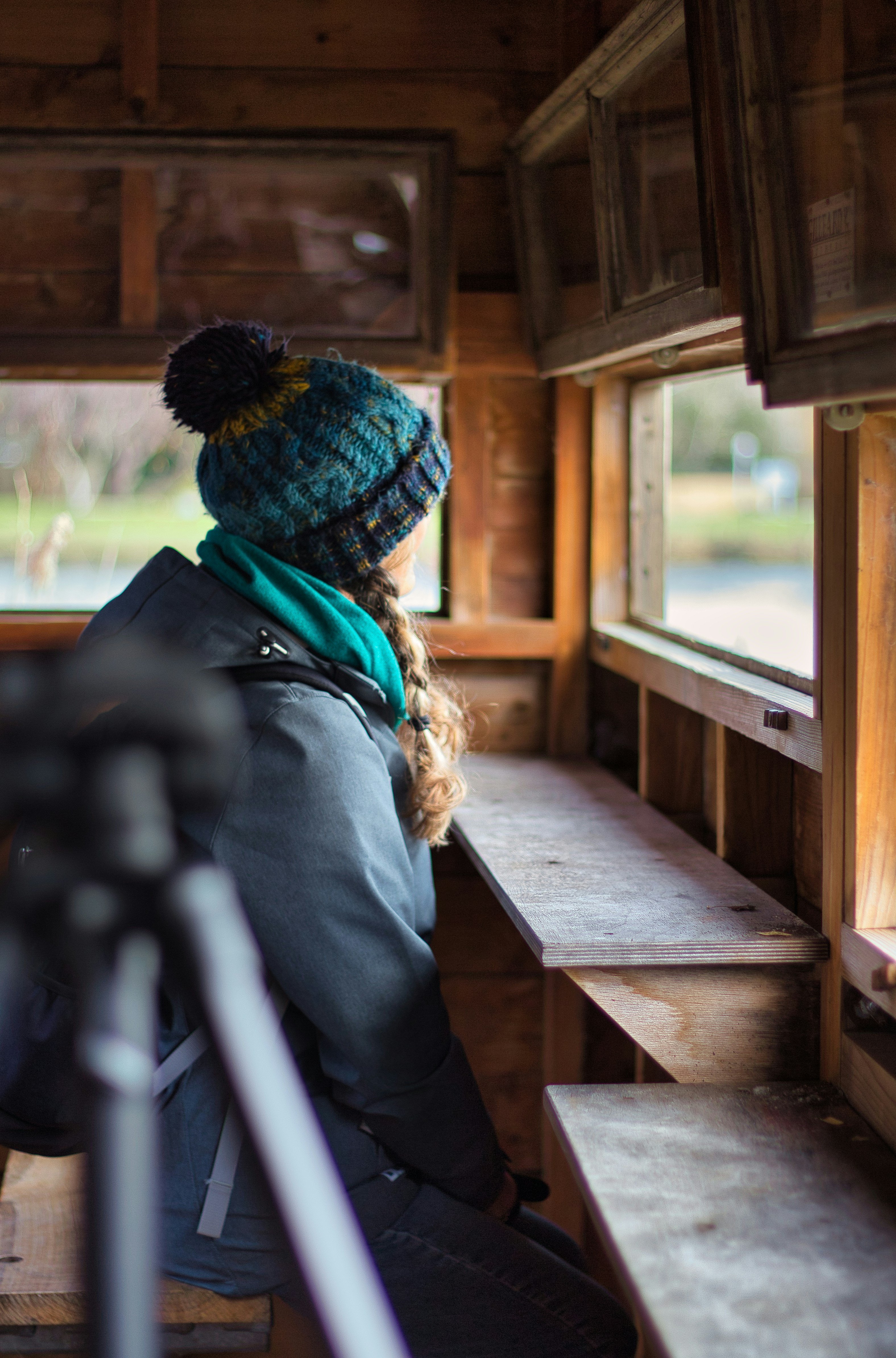 Woman looks out of a wooden bird watching hide.