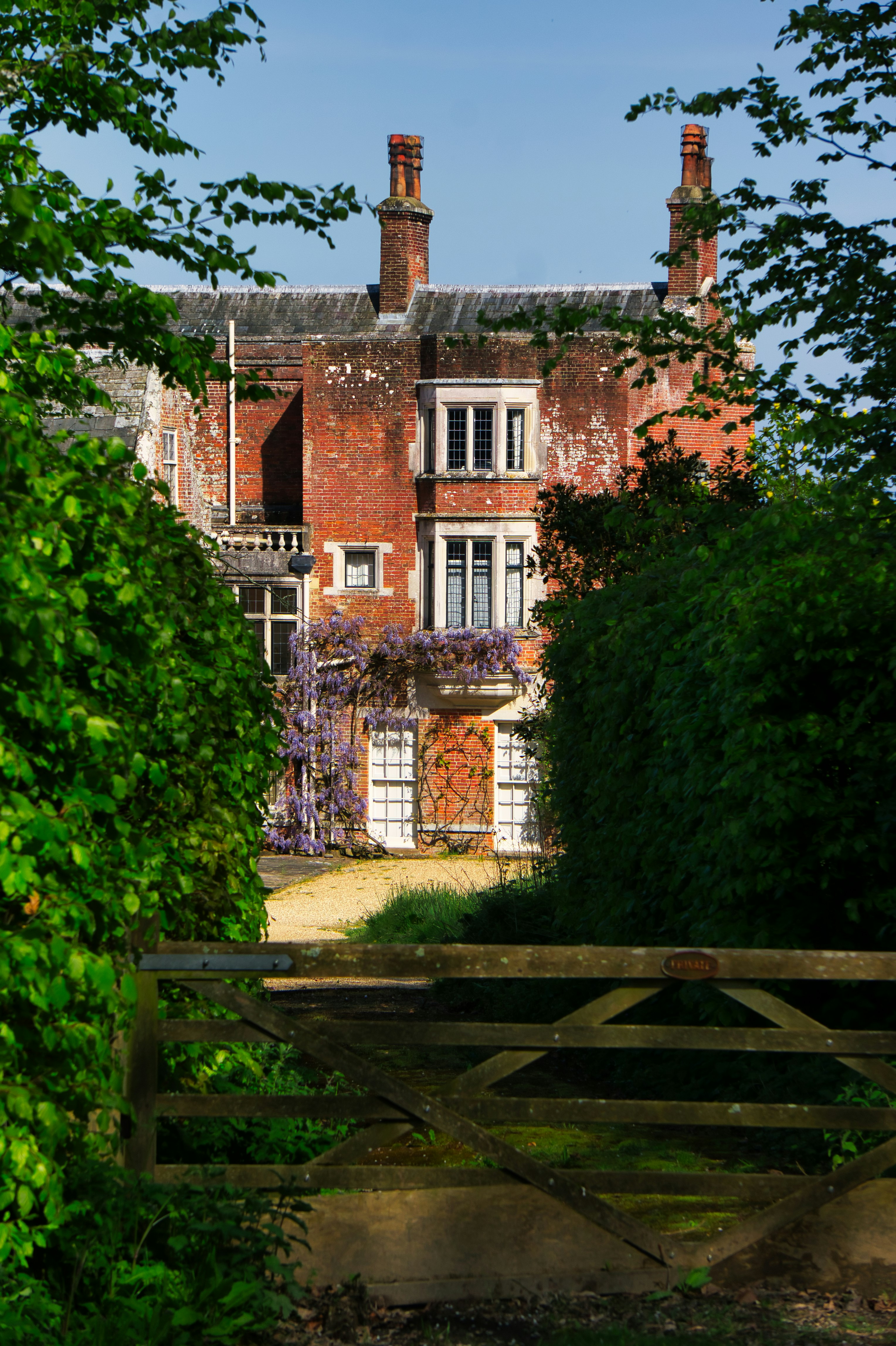 Old brick building framed by lush greenery.