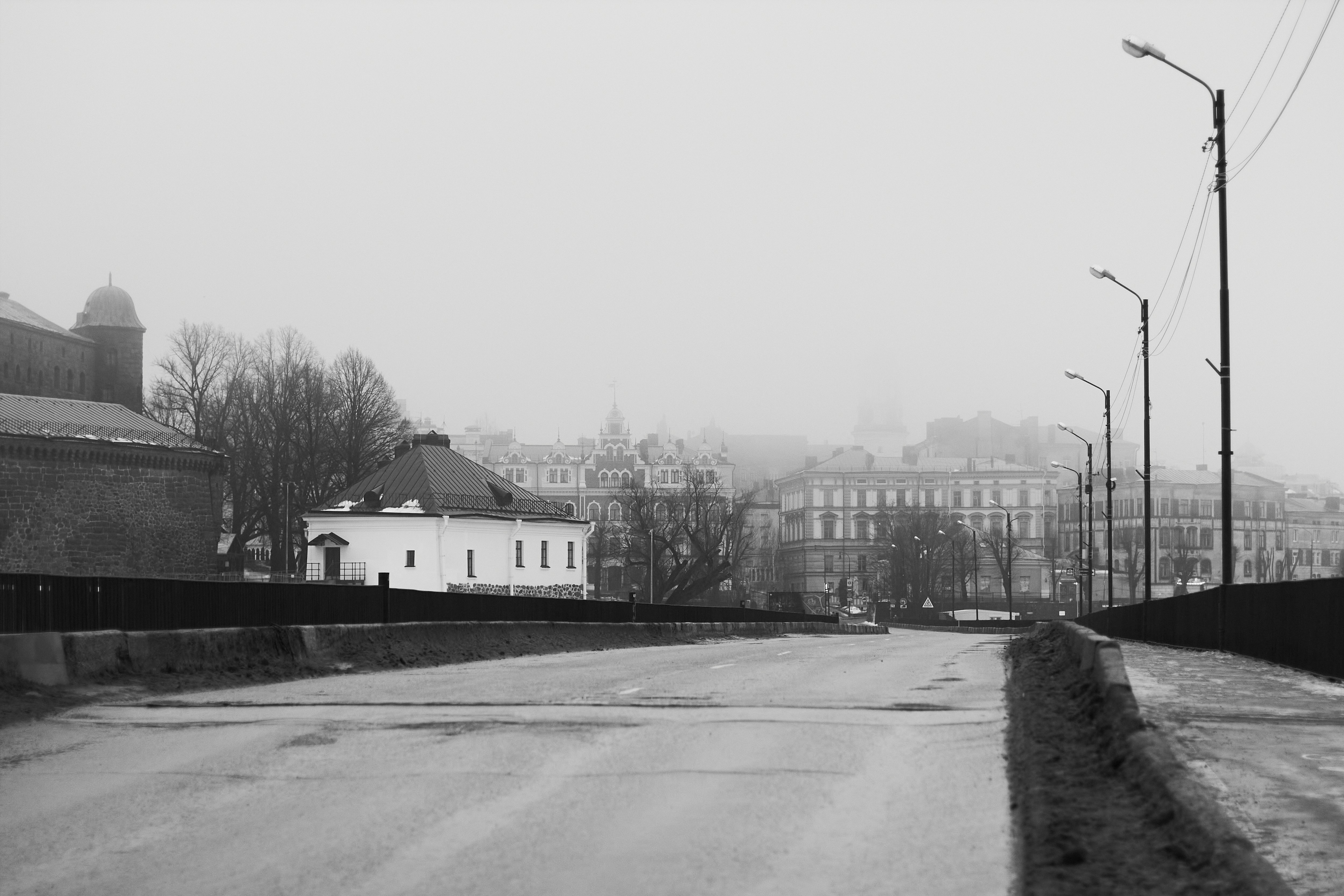 Gloomy bridge leads towards a foggy cityscape.