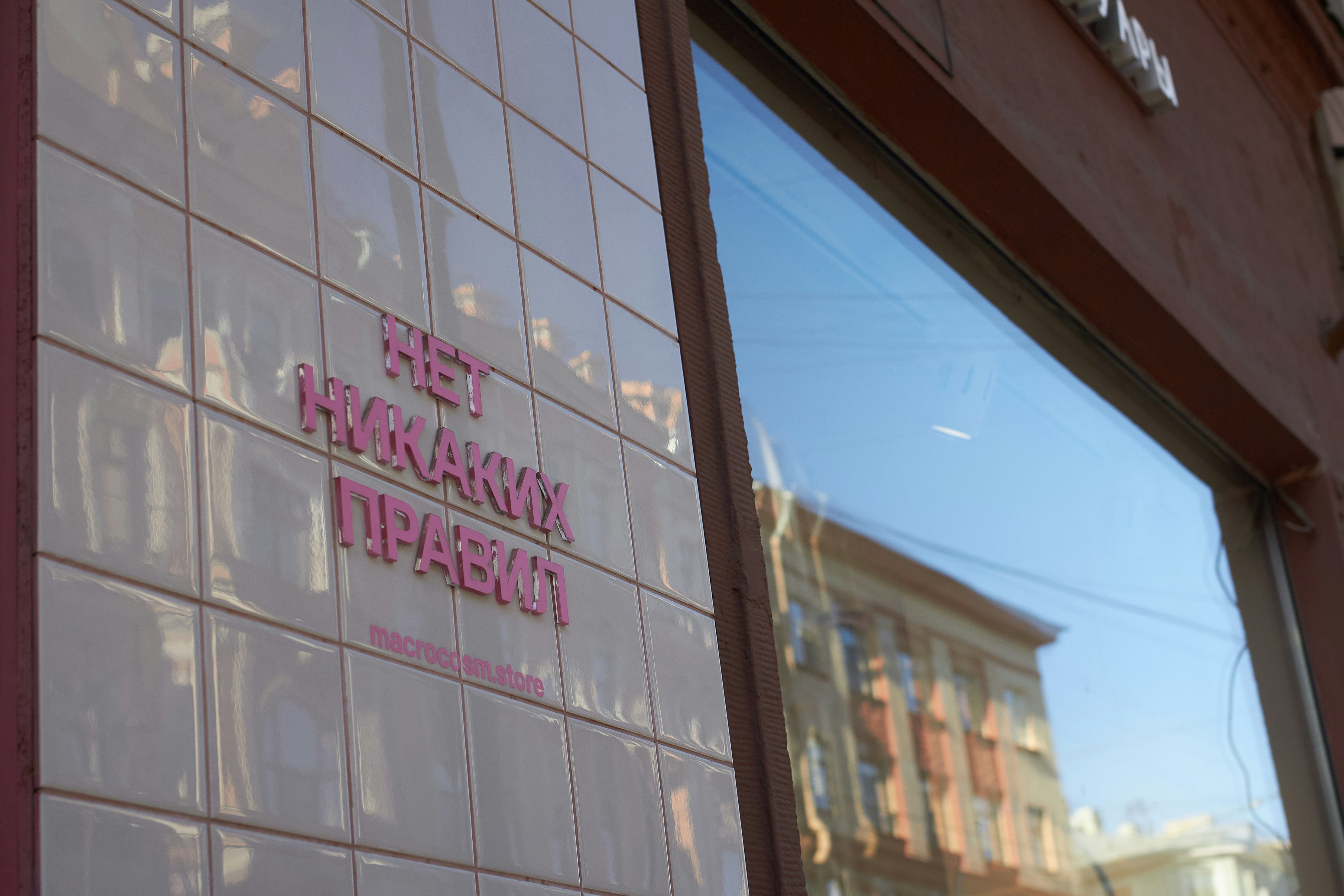 Pink tiles with russian text next to a window.