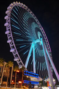 A ferris wheel glows at night with blue lights