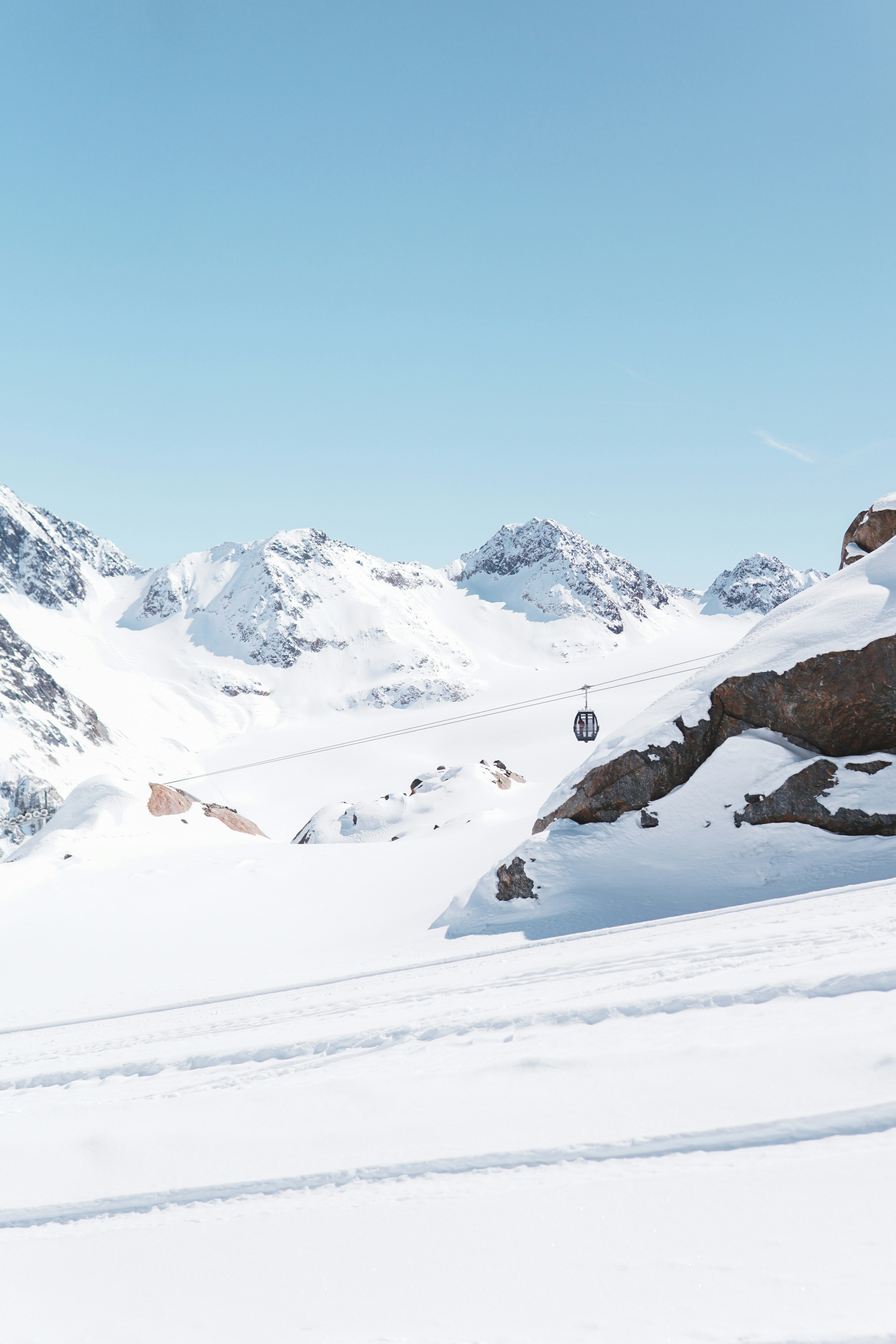 Snowy mountains with a cable car under a bright blue sky.