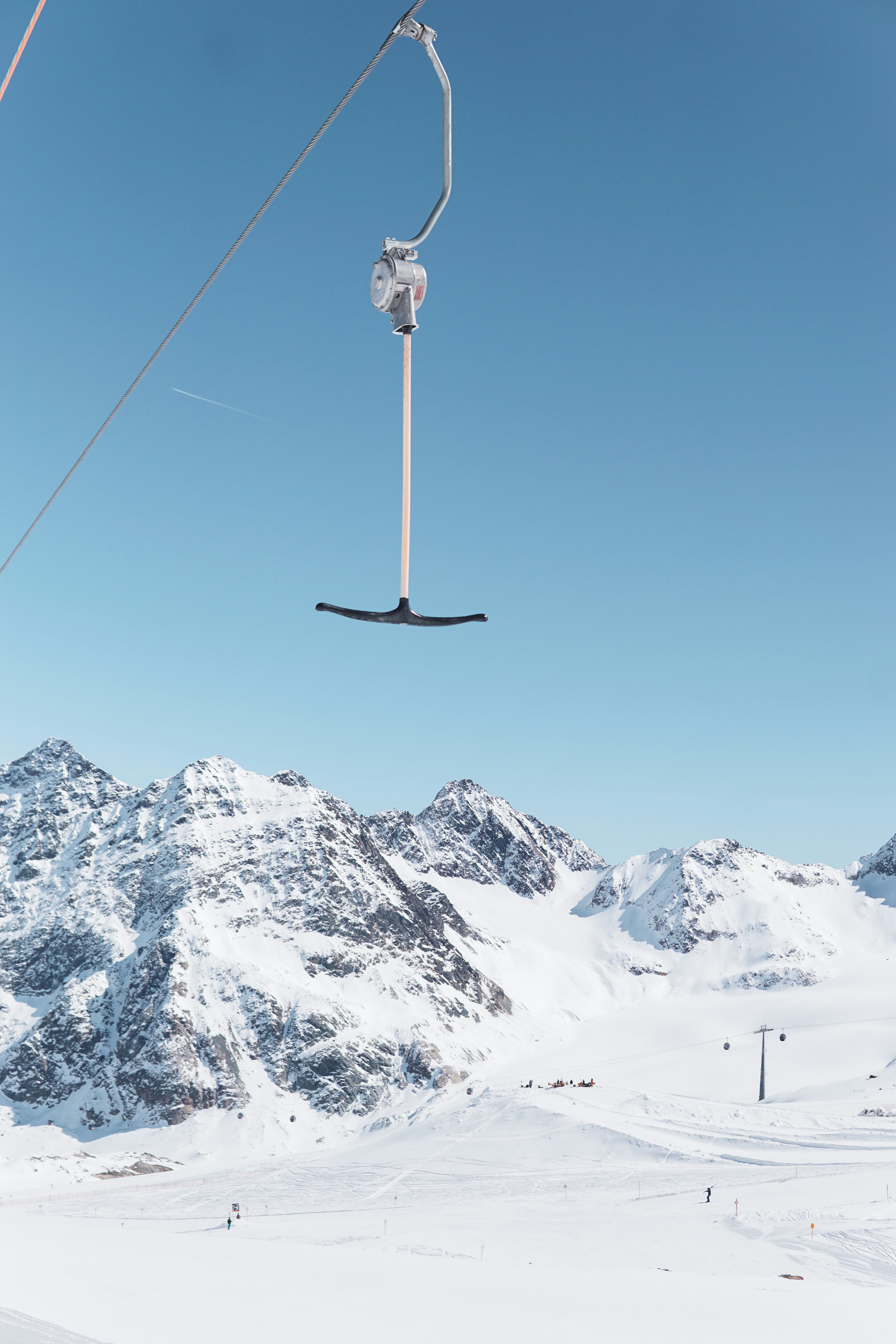 A t-bar ski lift overlooking snowy mountains.