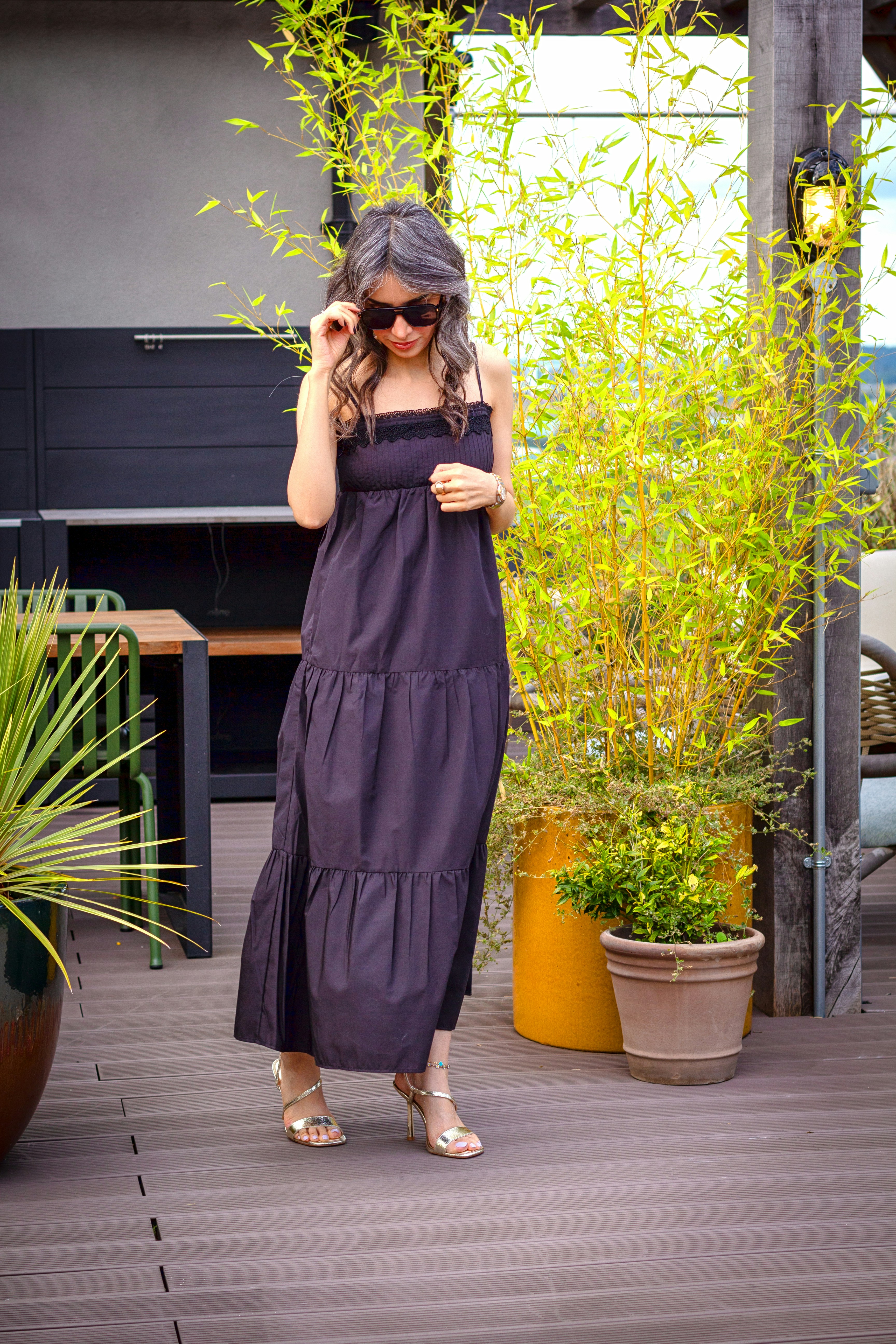A woman models a black maxi dress outside.