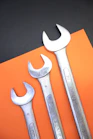 Three wrenches are arranged on orange and black paper