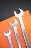 Three wrenches are arranged on orange and black paper