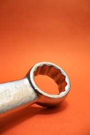 A wrench is displayed against an orange background.