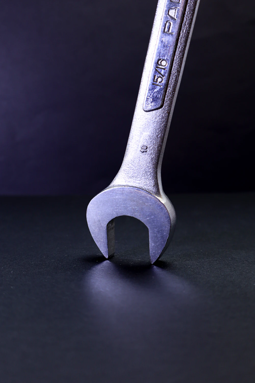 A wrench standing on a dark reflective surface