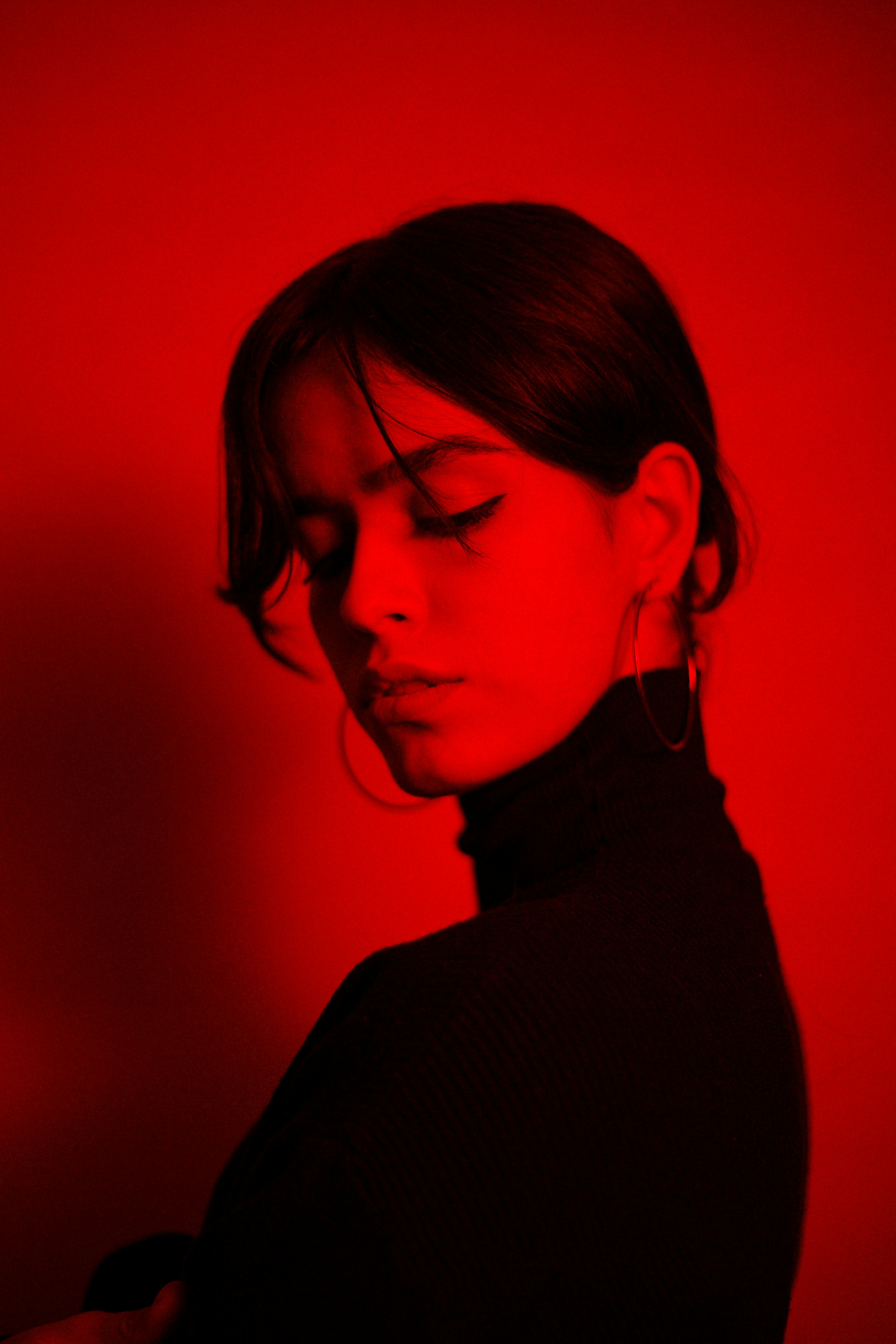 Woman in black turtleneck, red lighting.