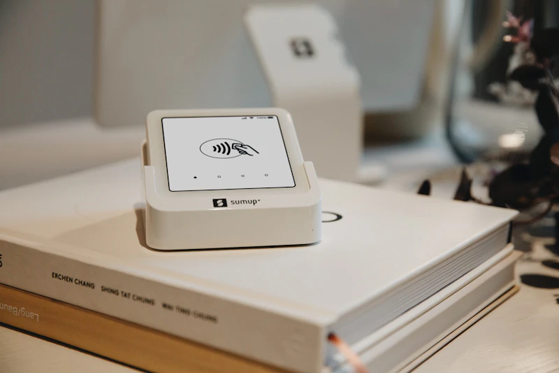 A contactless card payment terminal resting on a stack of books, representing the digital payment infrastructure most Barbadian small businesses still lack