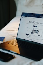 Laptop, phone, and card on a bed.